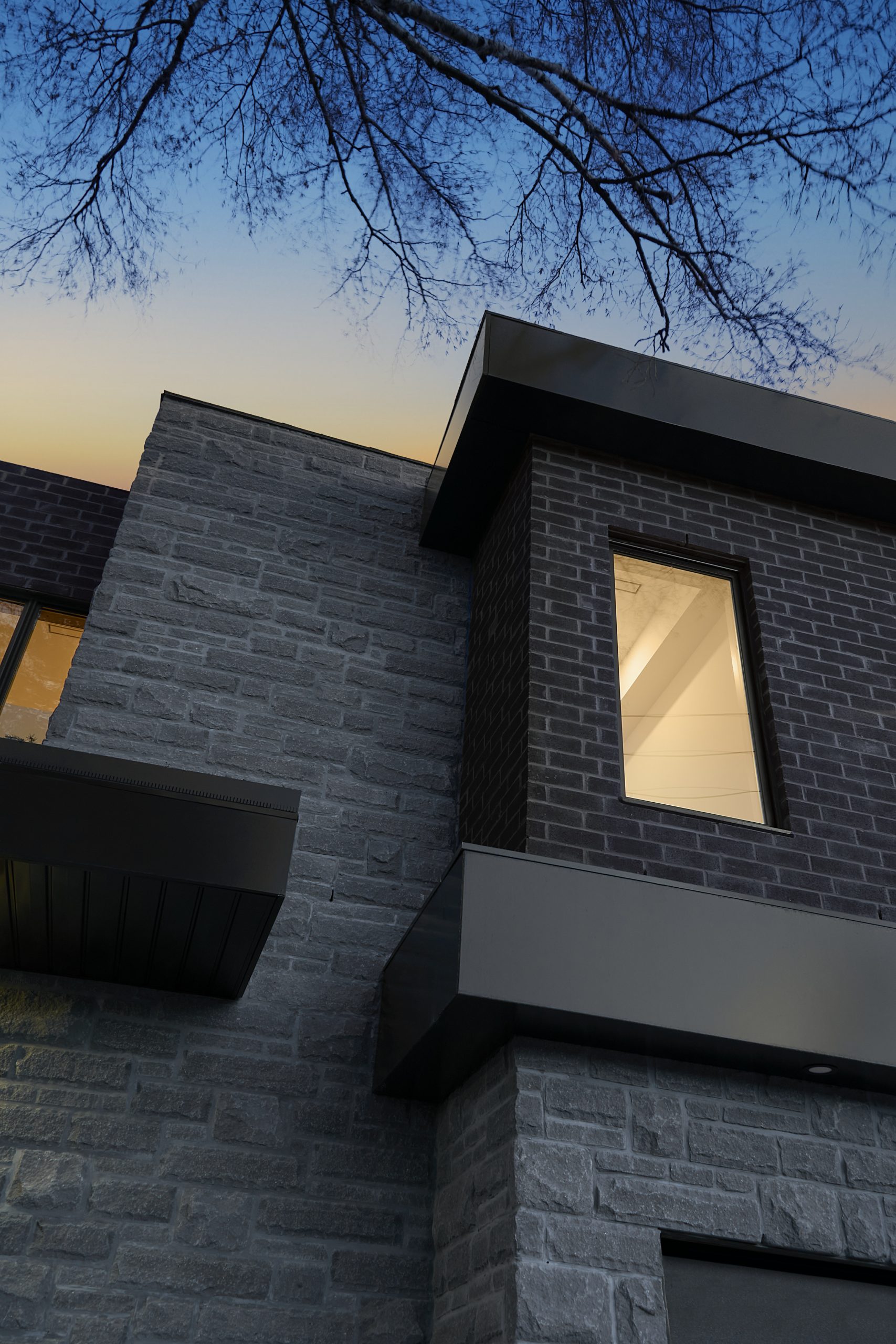 Close exterior view of black brick and recessed glazing