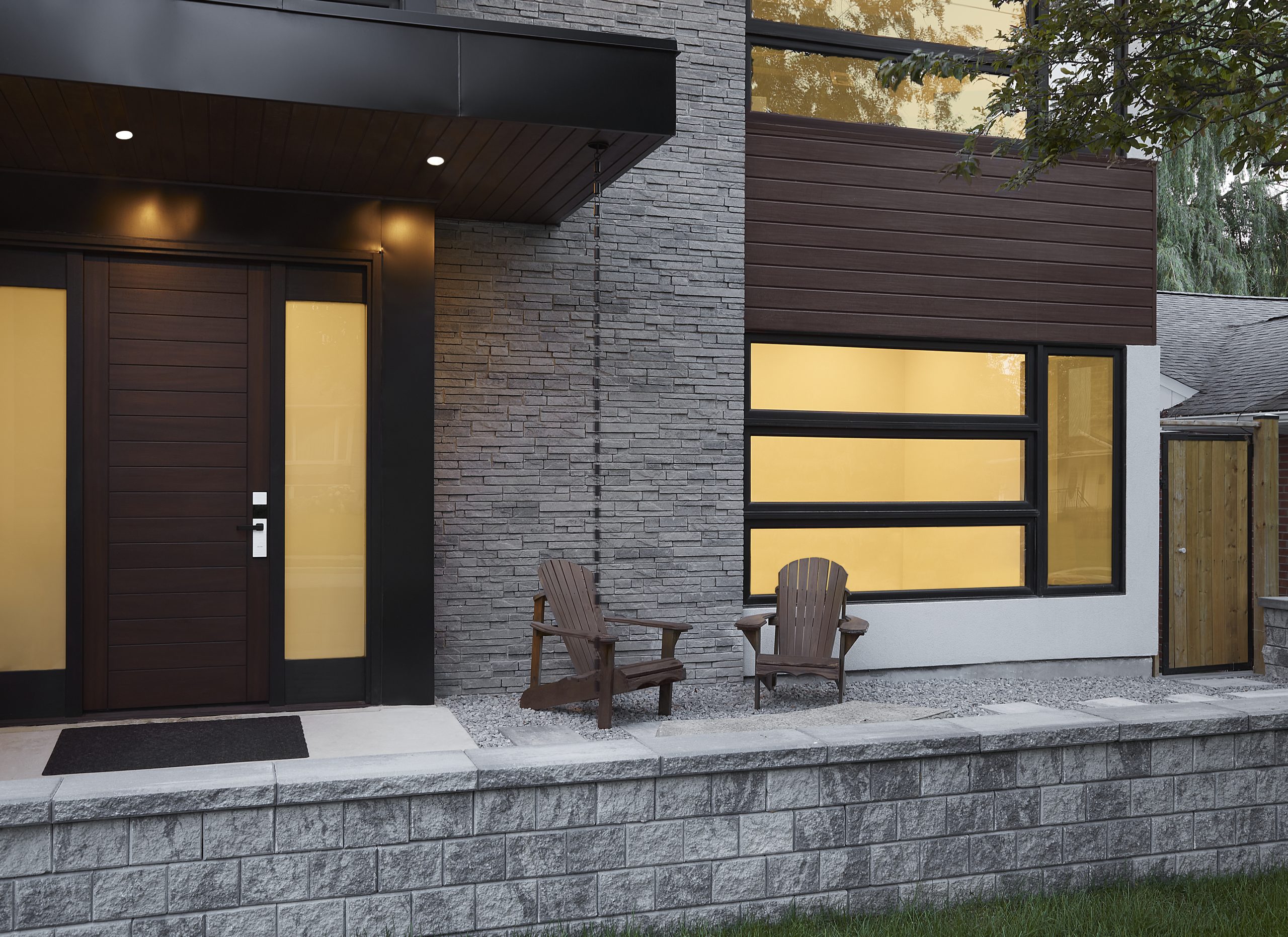 Stone, wood siding and broad windows beside the front entrance