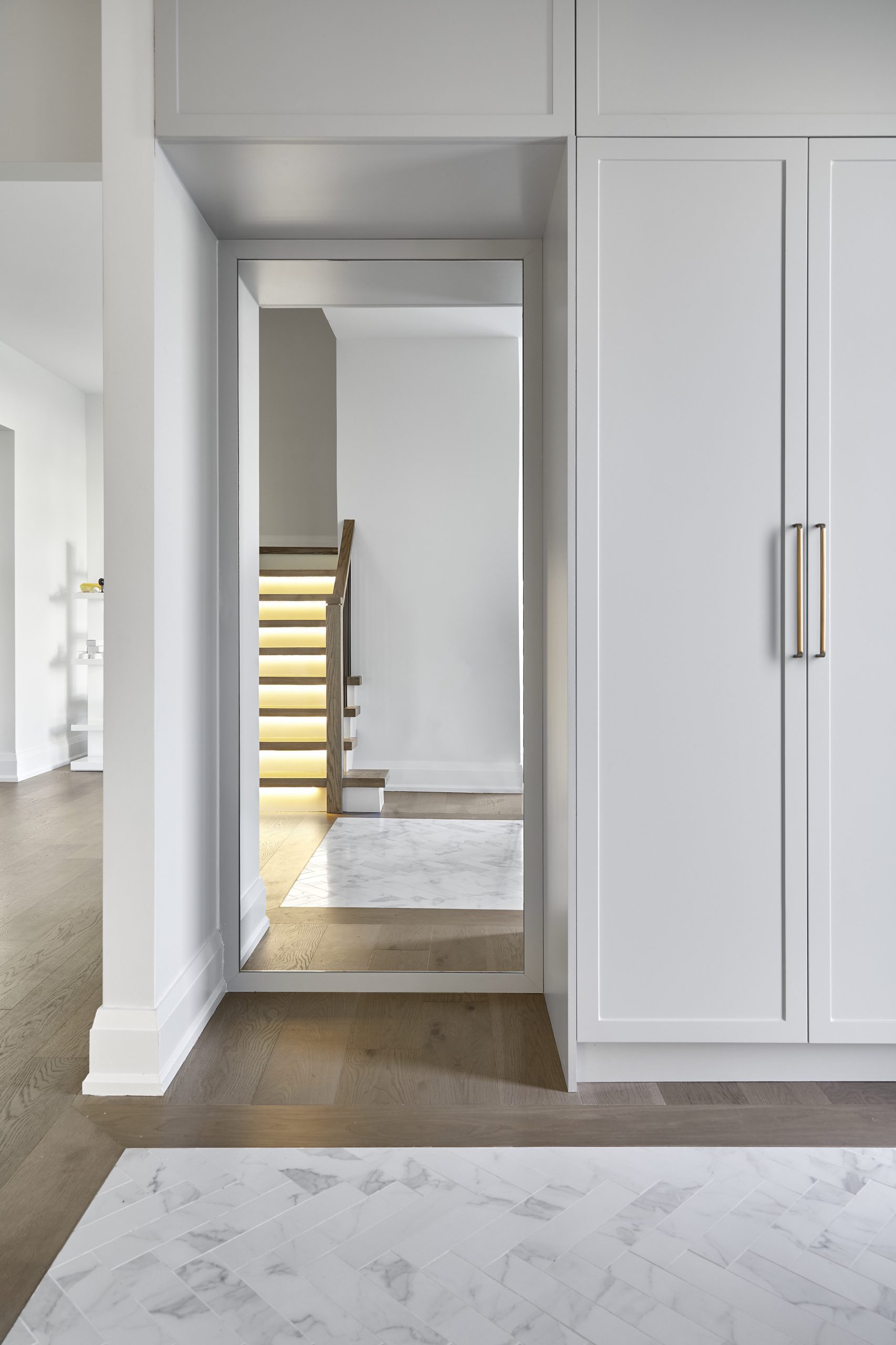 Bright hallway with integrated storage and illuminated stair details