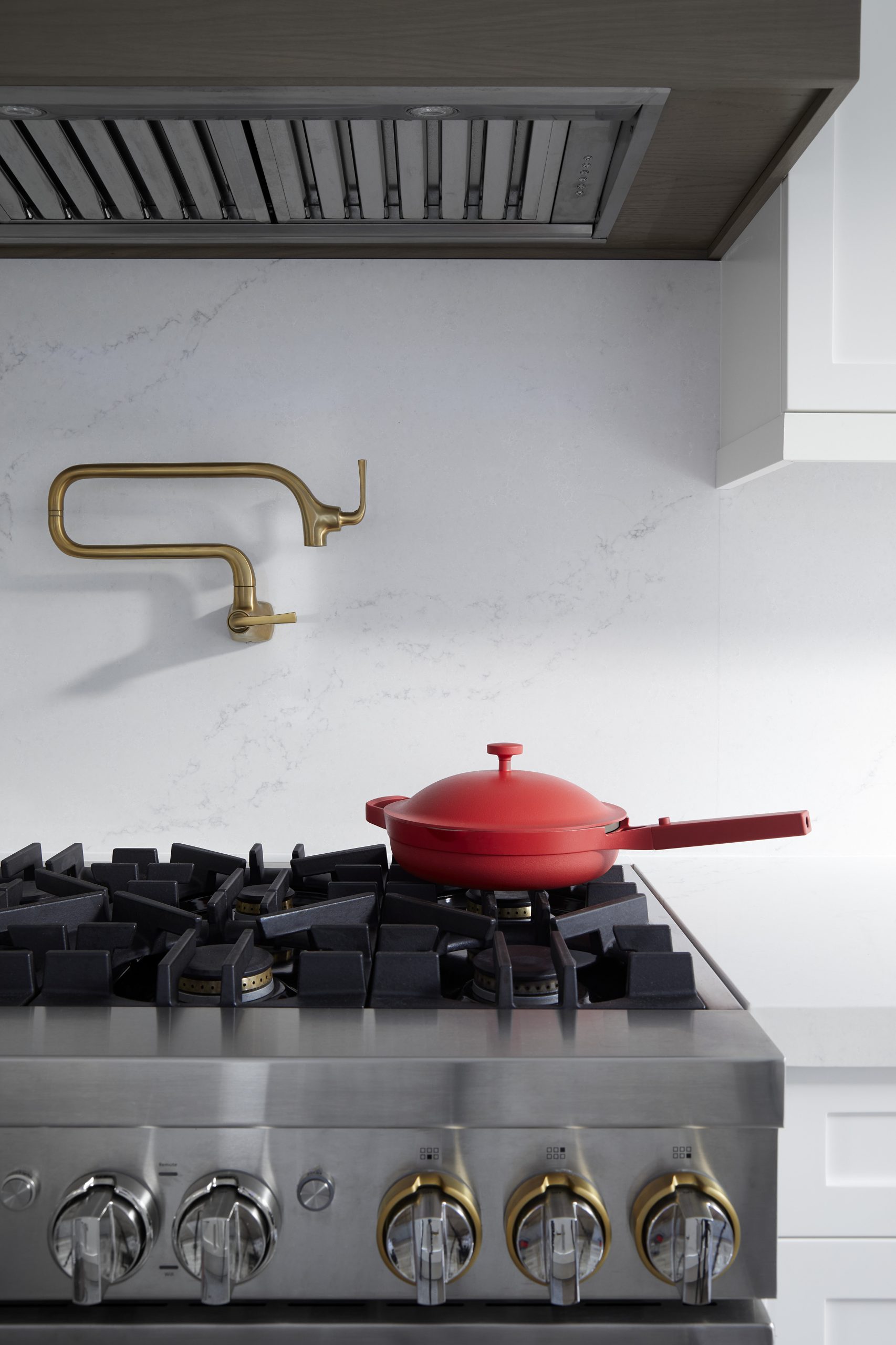Dark kitchen with brass fixtures and a red Dutch oven