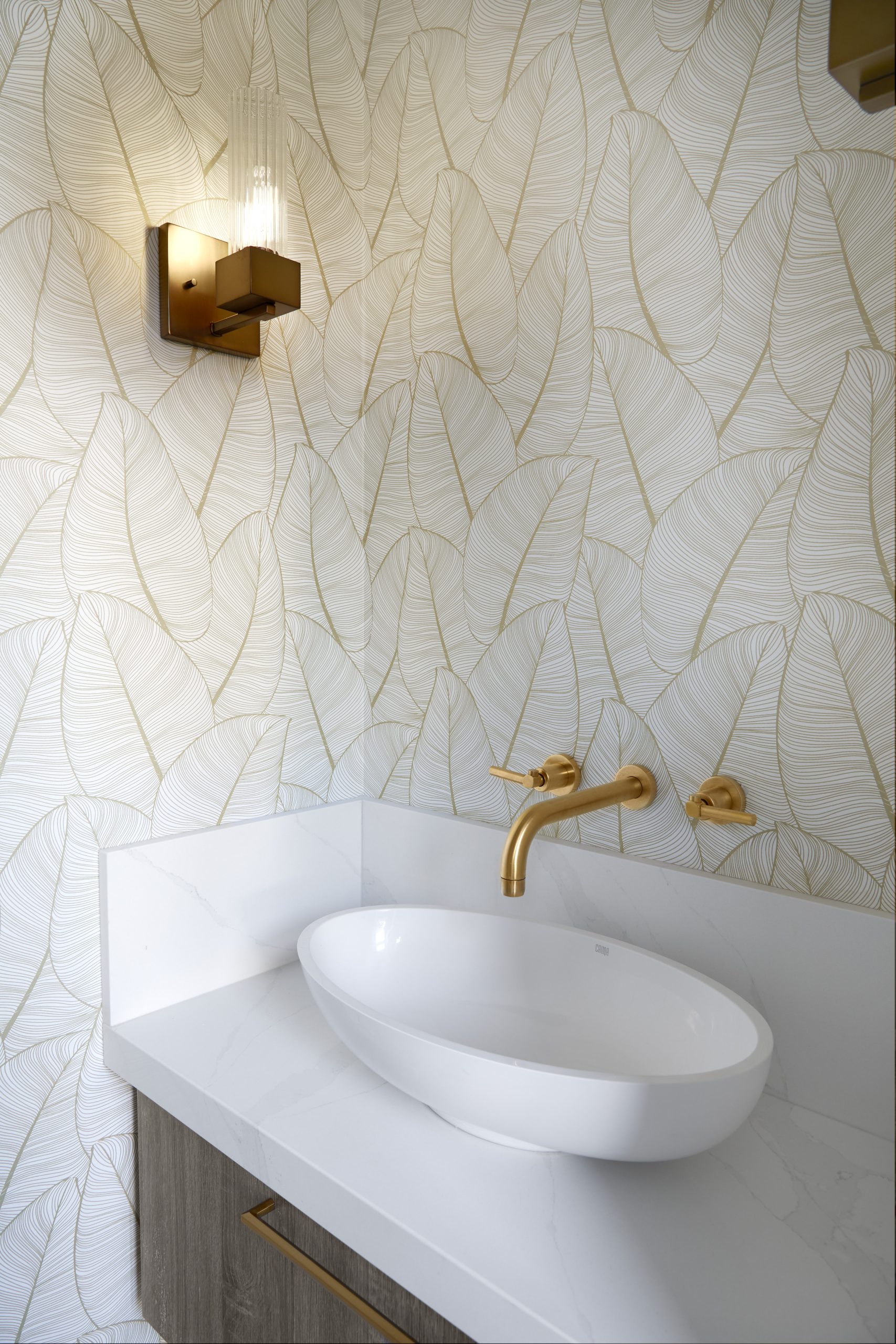 Marble powder room with a warm brass wall sconce