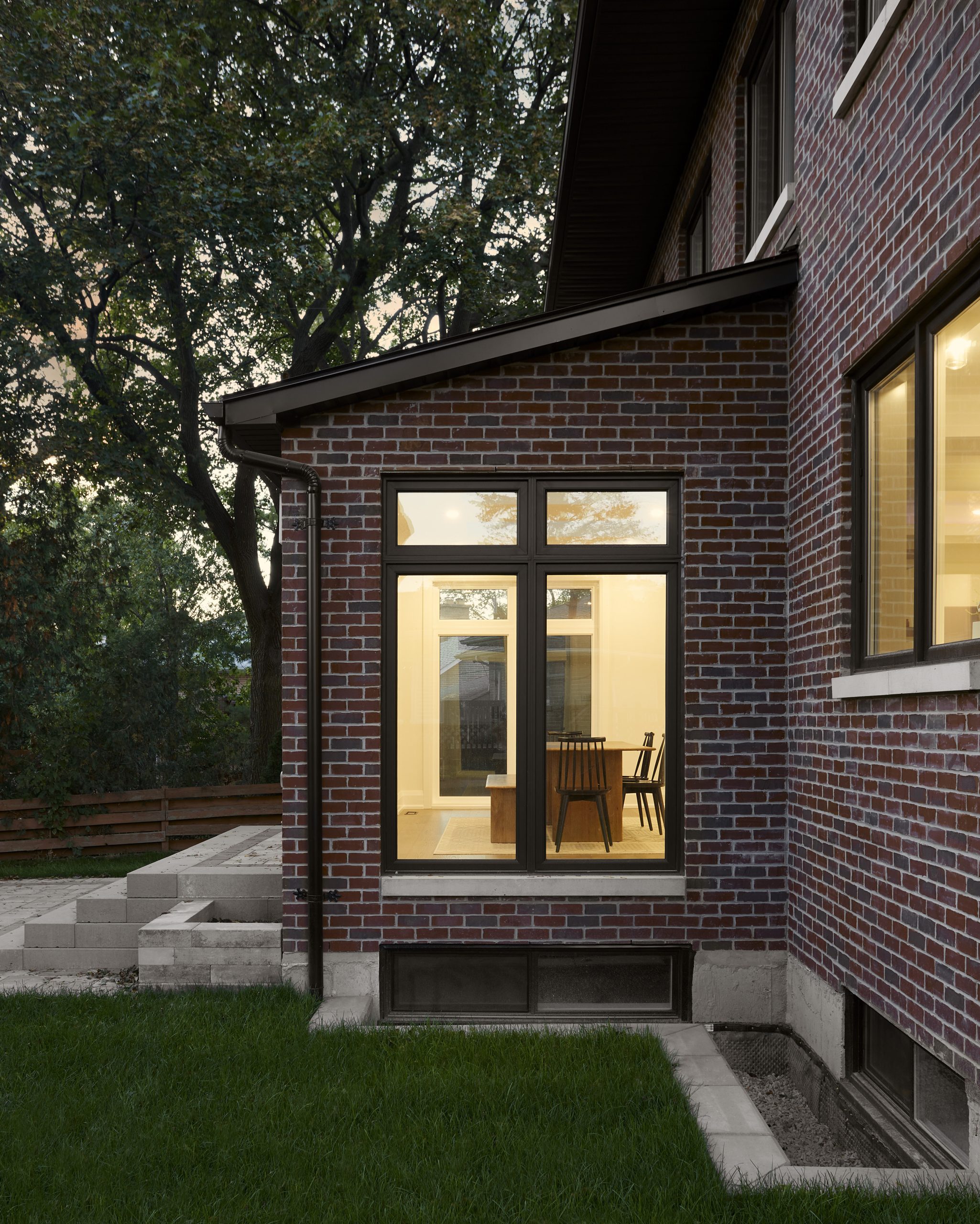 Glazed side entrance framed by mature landscaping