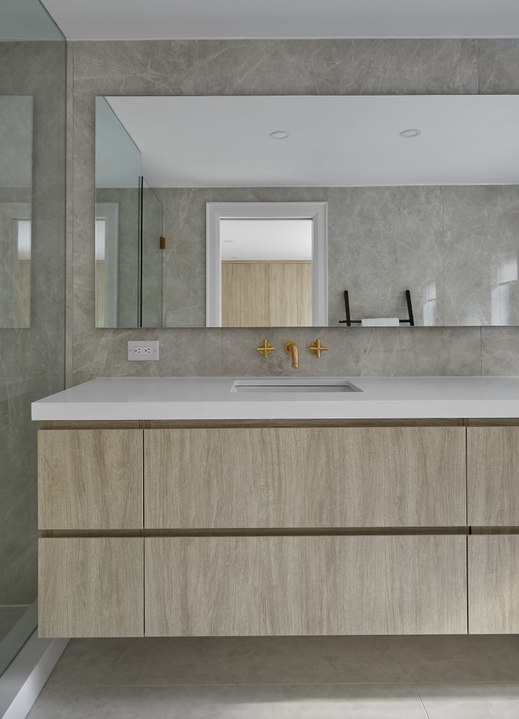 Bathroom vanity and large mirror under neutral overhead lighting