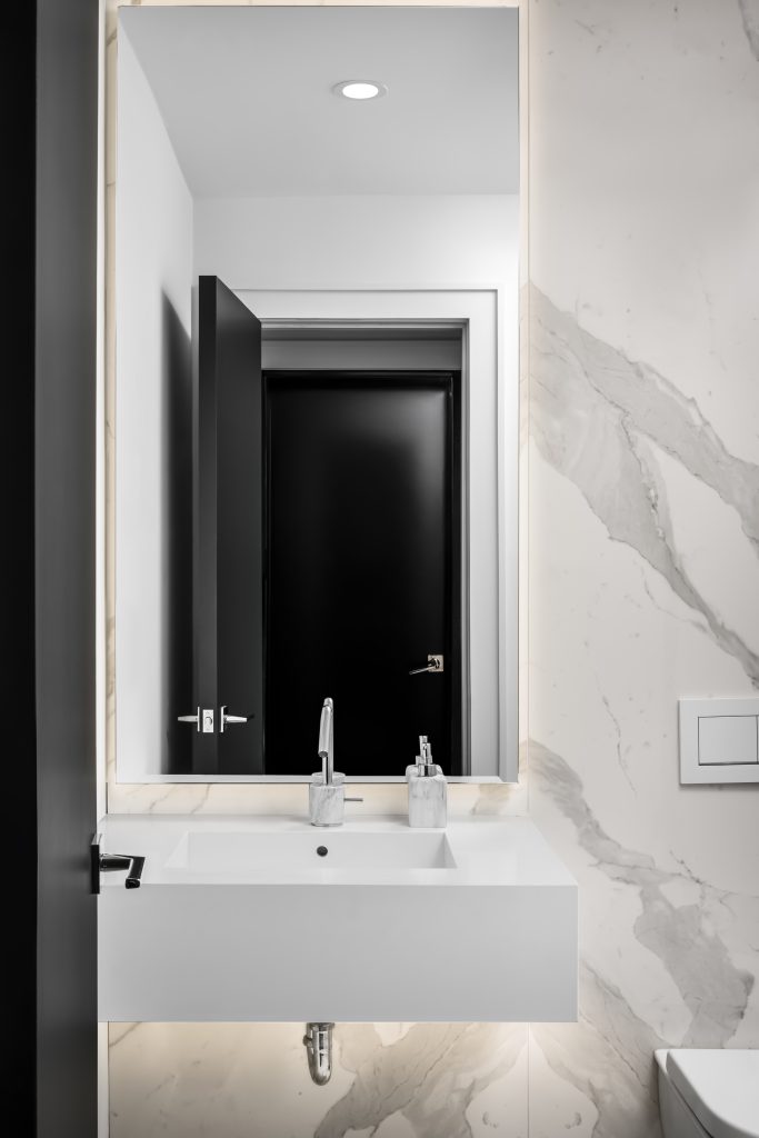 White marble bathroom with warm accent lighting around the vanity