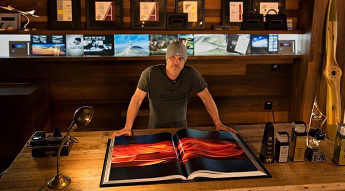 Peter Lik leaning over a large open photography book in his studio