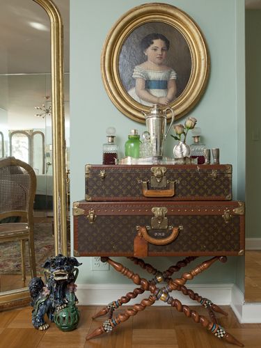 Stacked Louis Vuitton cases displayed below a framed portrait