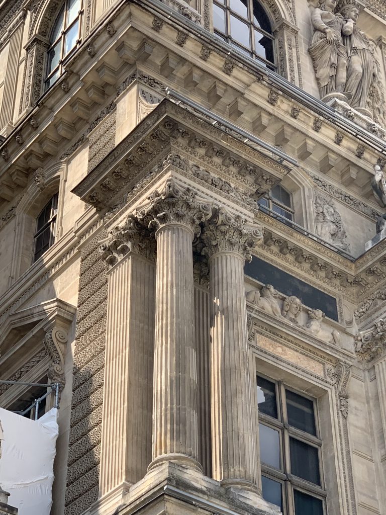 Paired classical columns and carved relief on the Louvre exterior