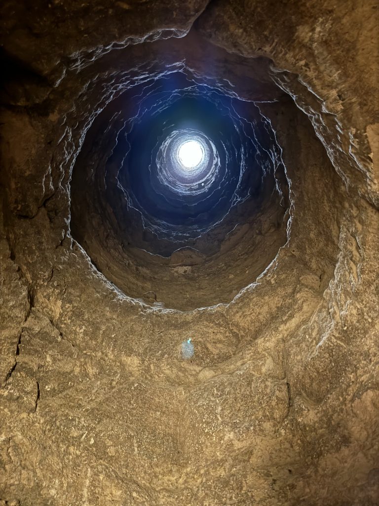 Circular stone shaft viewed upward toward daylight