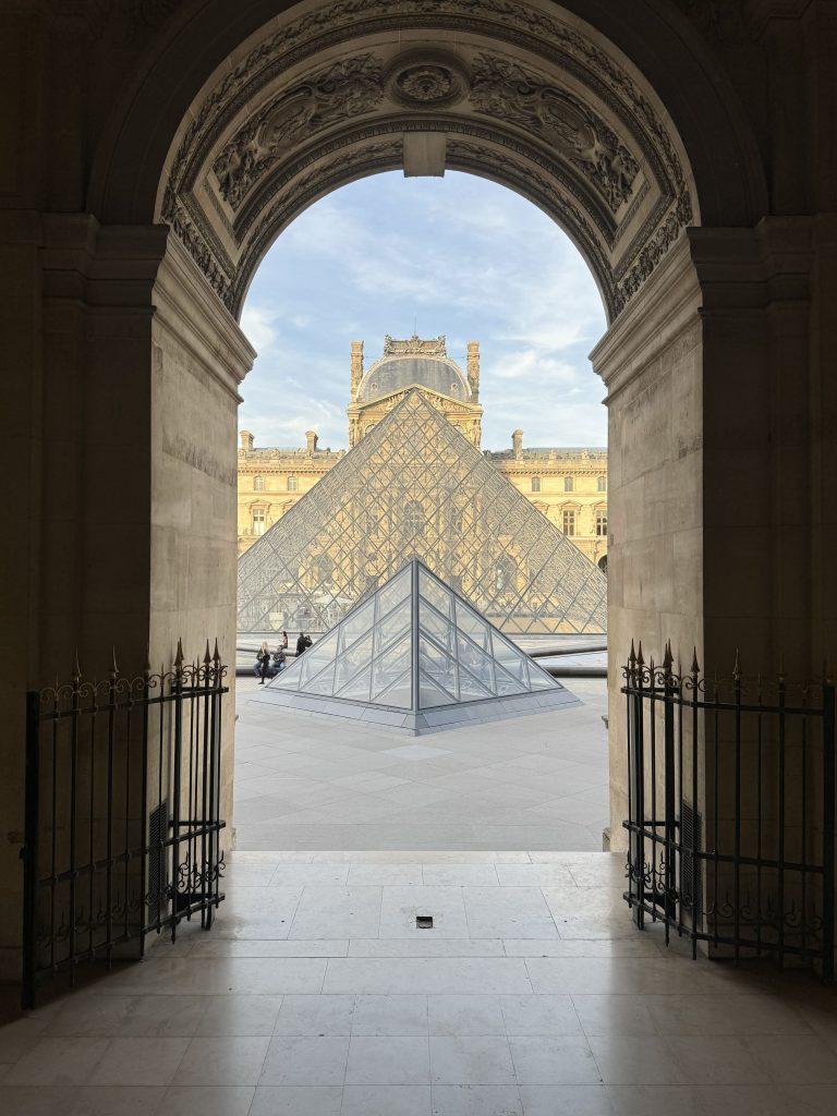 Louvre glass pyramid framed by a stone archway