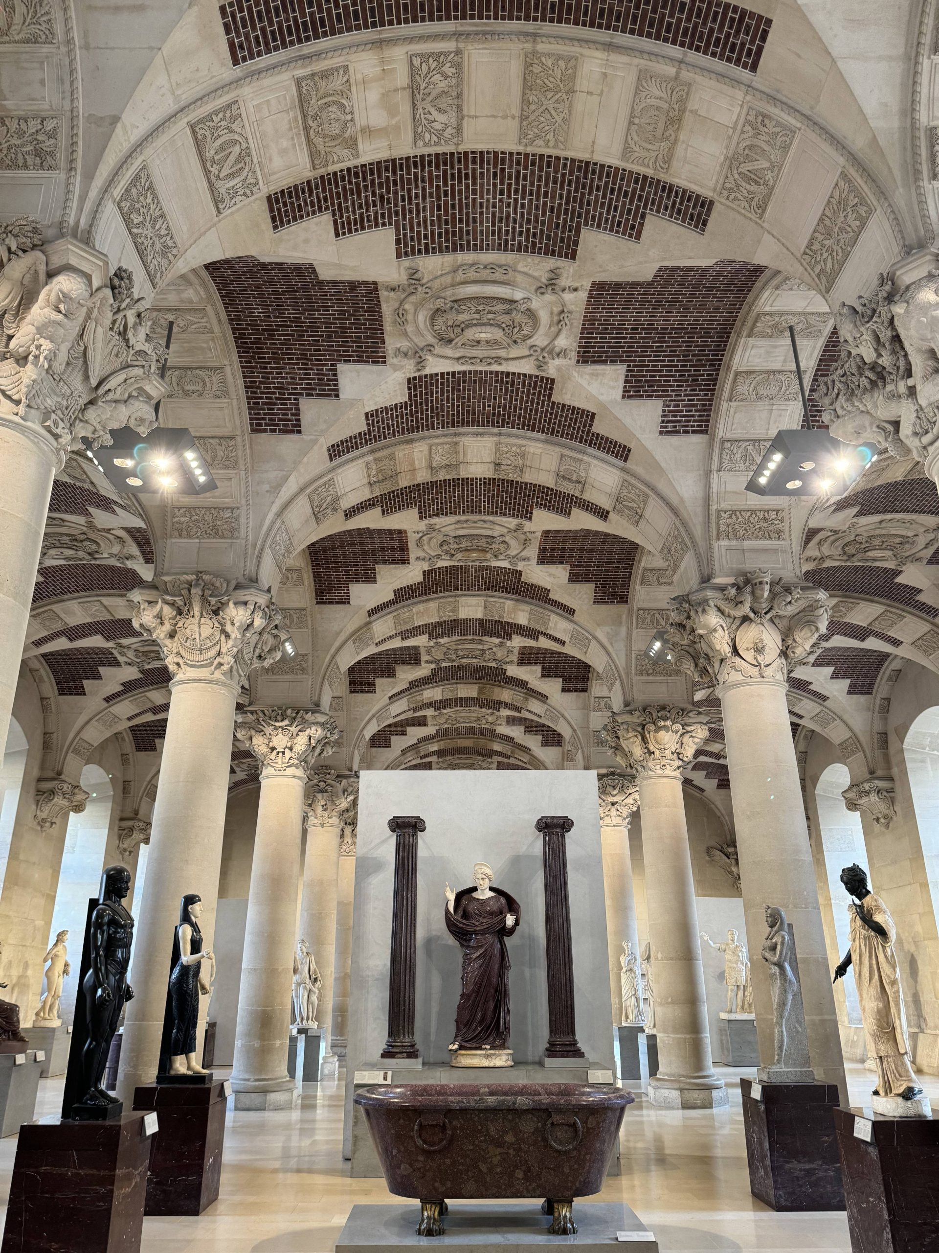 Sculpture gallery with a patterned vaulted ceiling and visitors