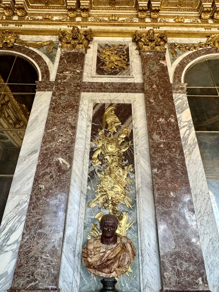 Portrait bust set against marble panels and gilded decoration