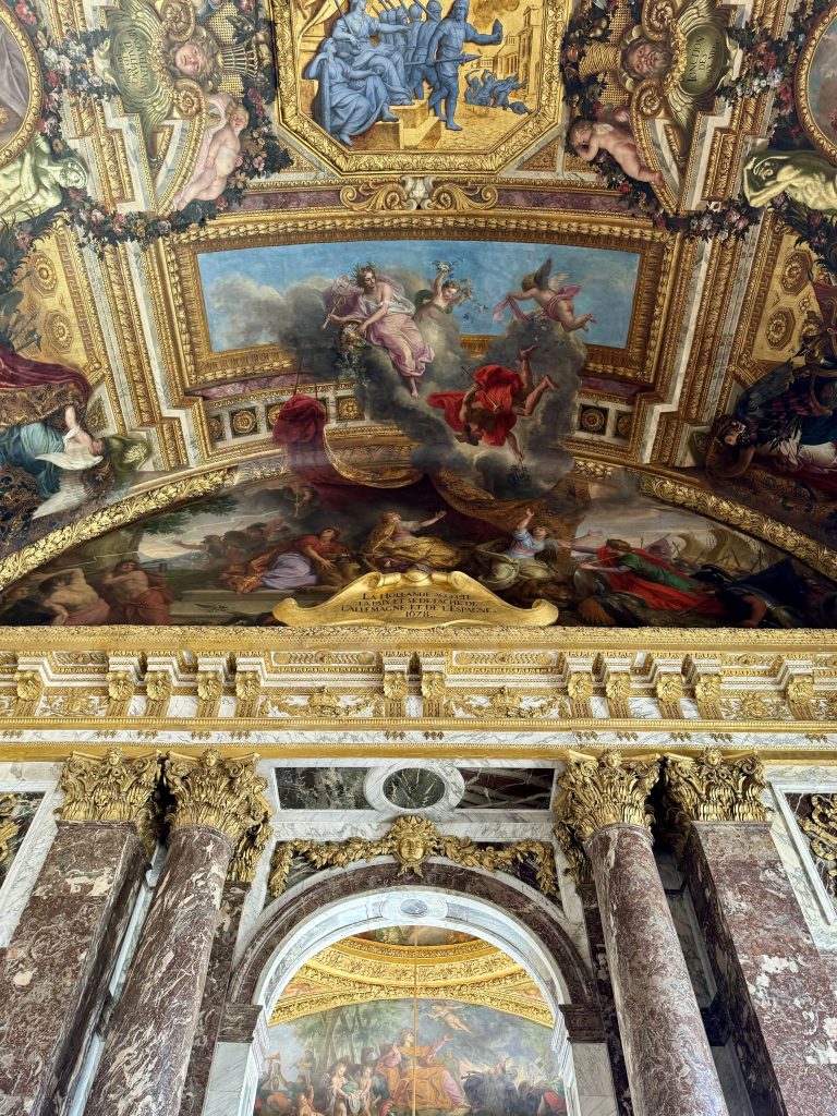 Painted ceiling with sculptural gilded framing above an arched doorway