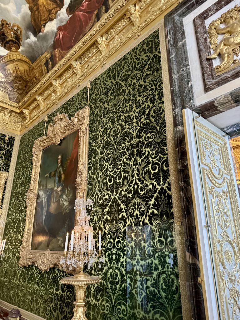 Green patterned wall covering with gilded framing and a portrait