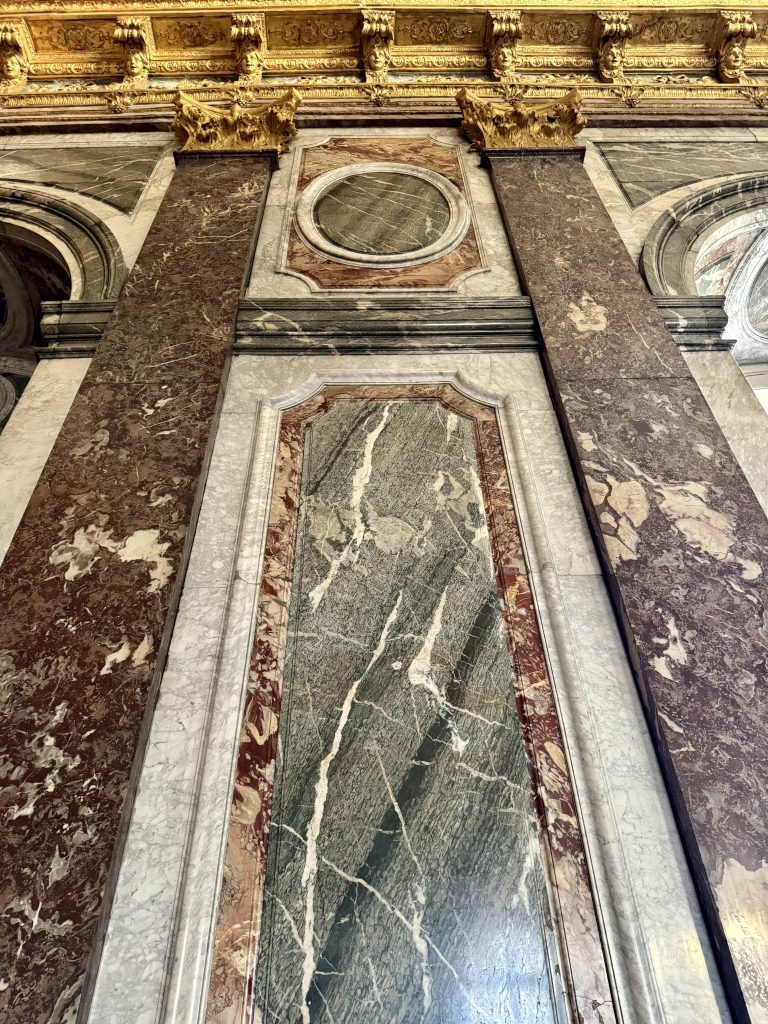 Veined marble wall panels framed by gilded architectural decoration