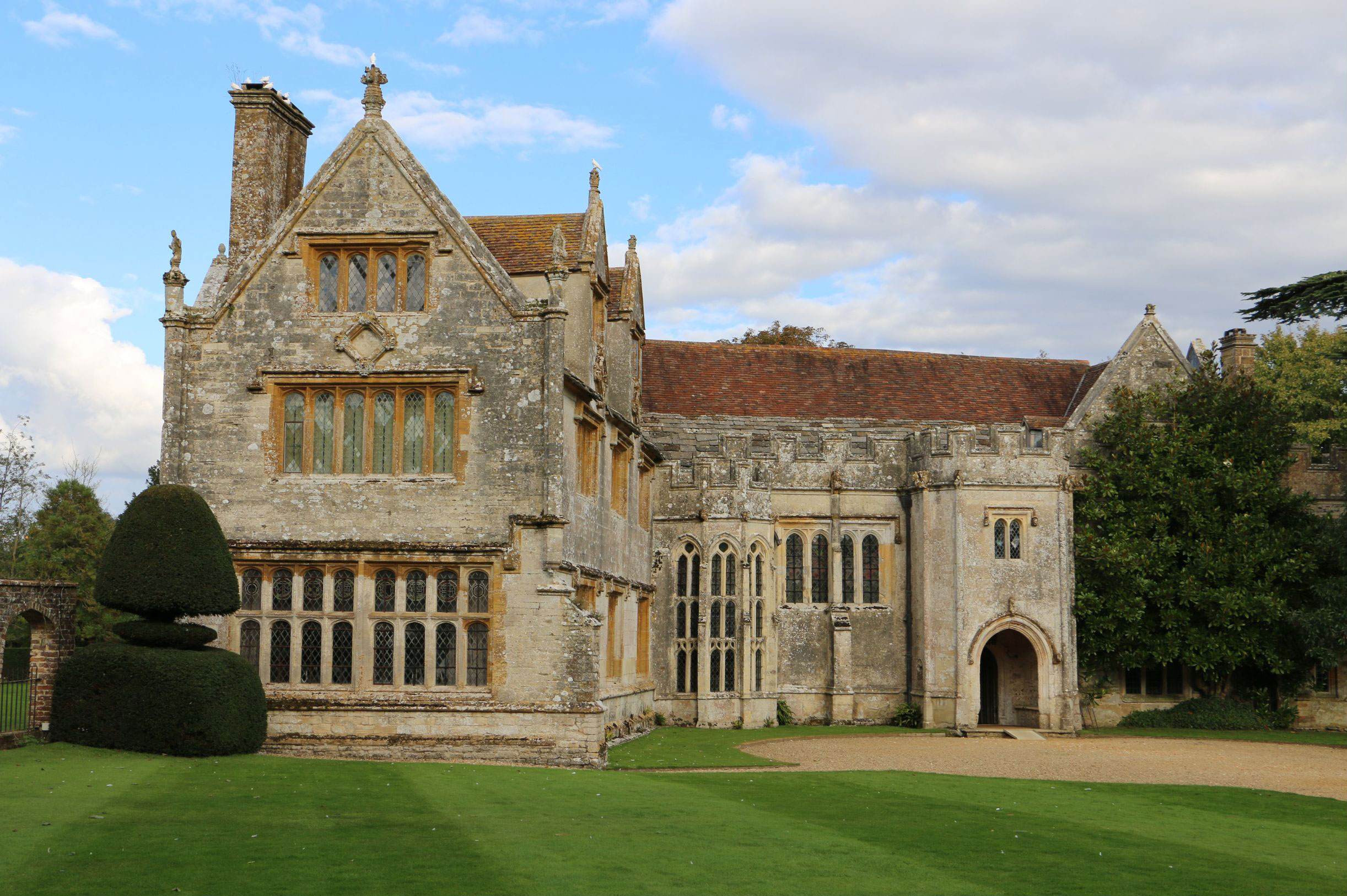 Historic stone manor and clipped planting beyond a broad lawn