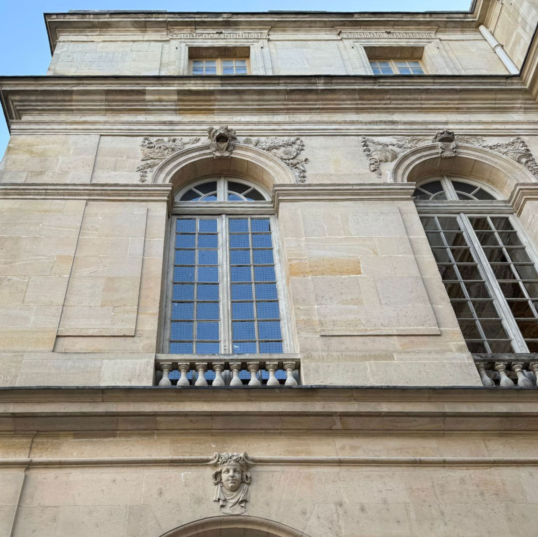 Pale stone facade with tall arched window surrounds