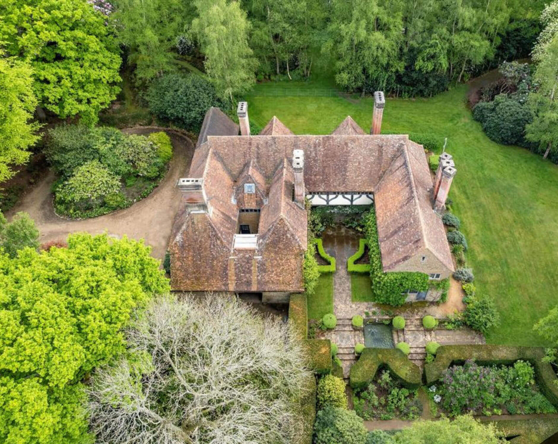 Aerial view of a tiled-roof country house and garden