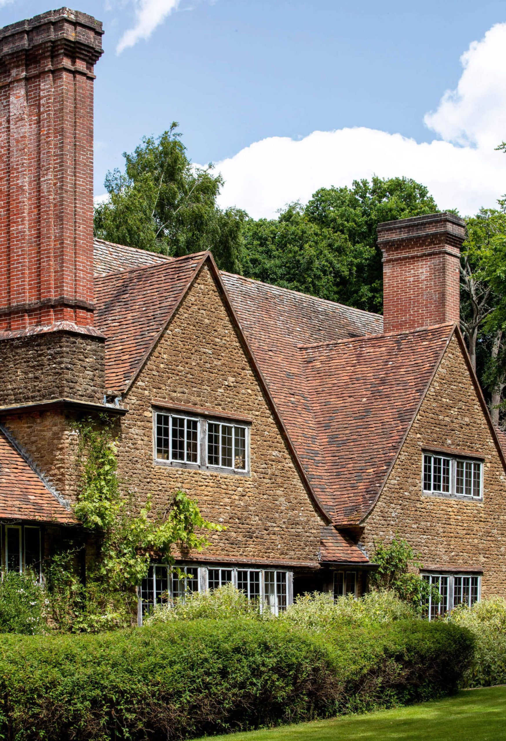Gabled house with tall brick chimneys and clipped hedges