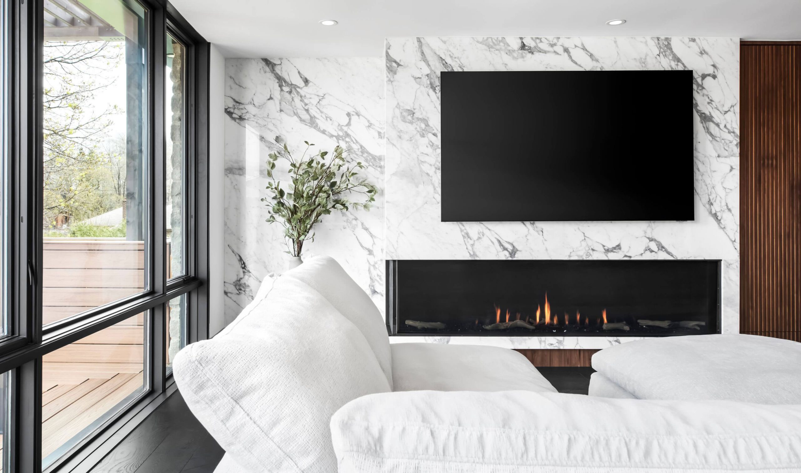 Pale upholstered seating beside a marble fireplace