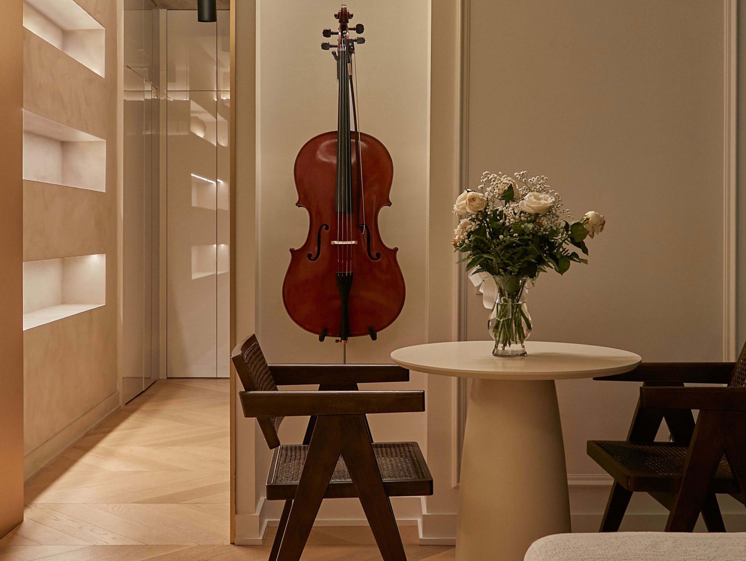 Cello and flowers beside a round table in a warm interior