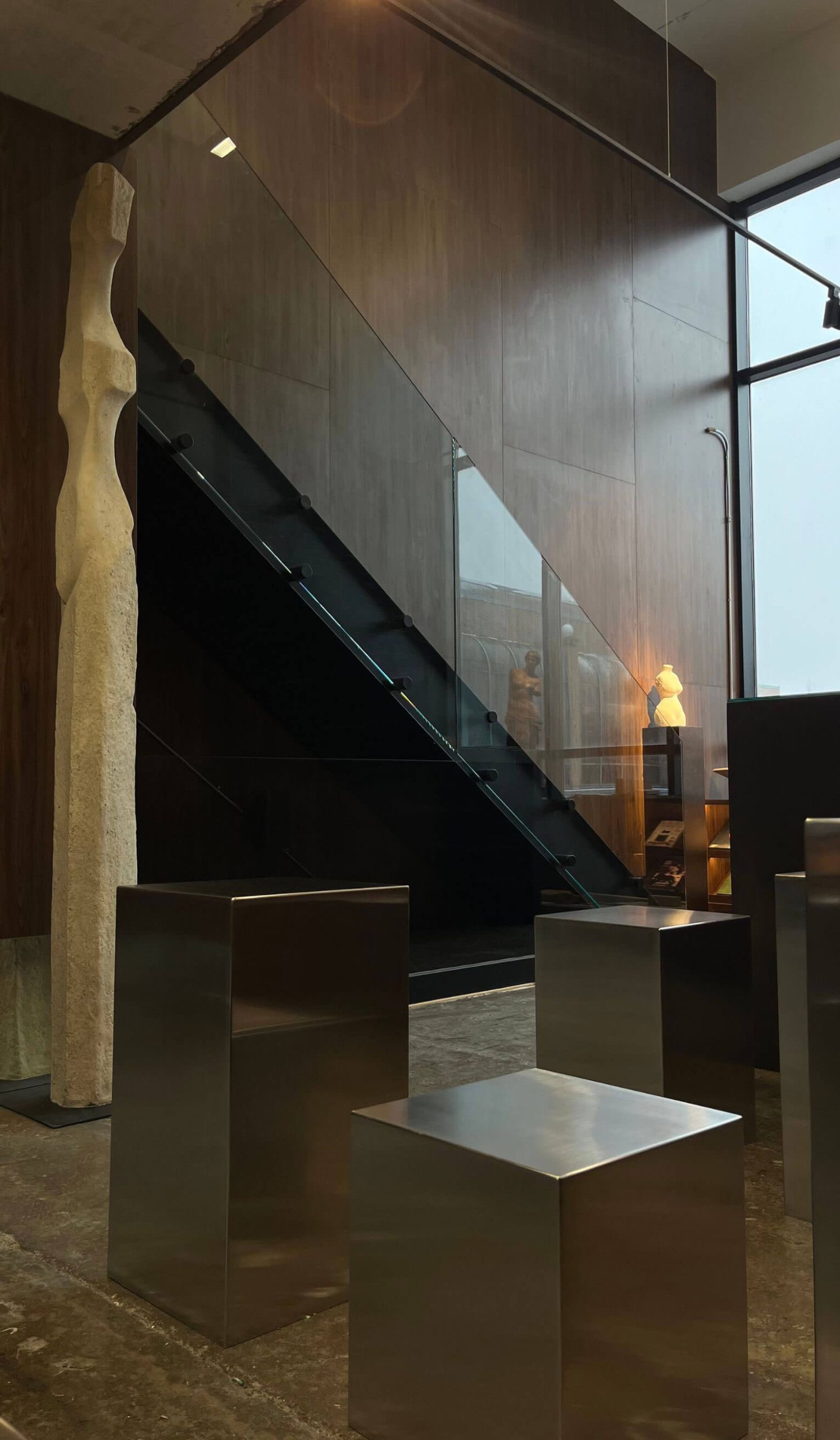 Sculpture beneath a staircase in a softly lit interior