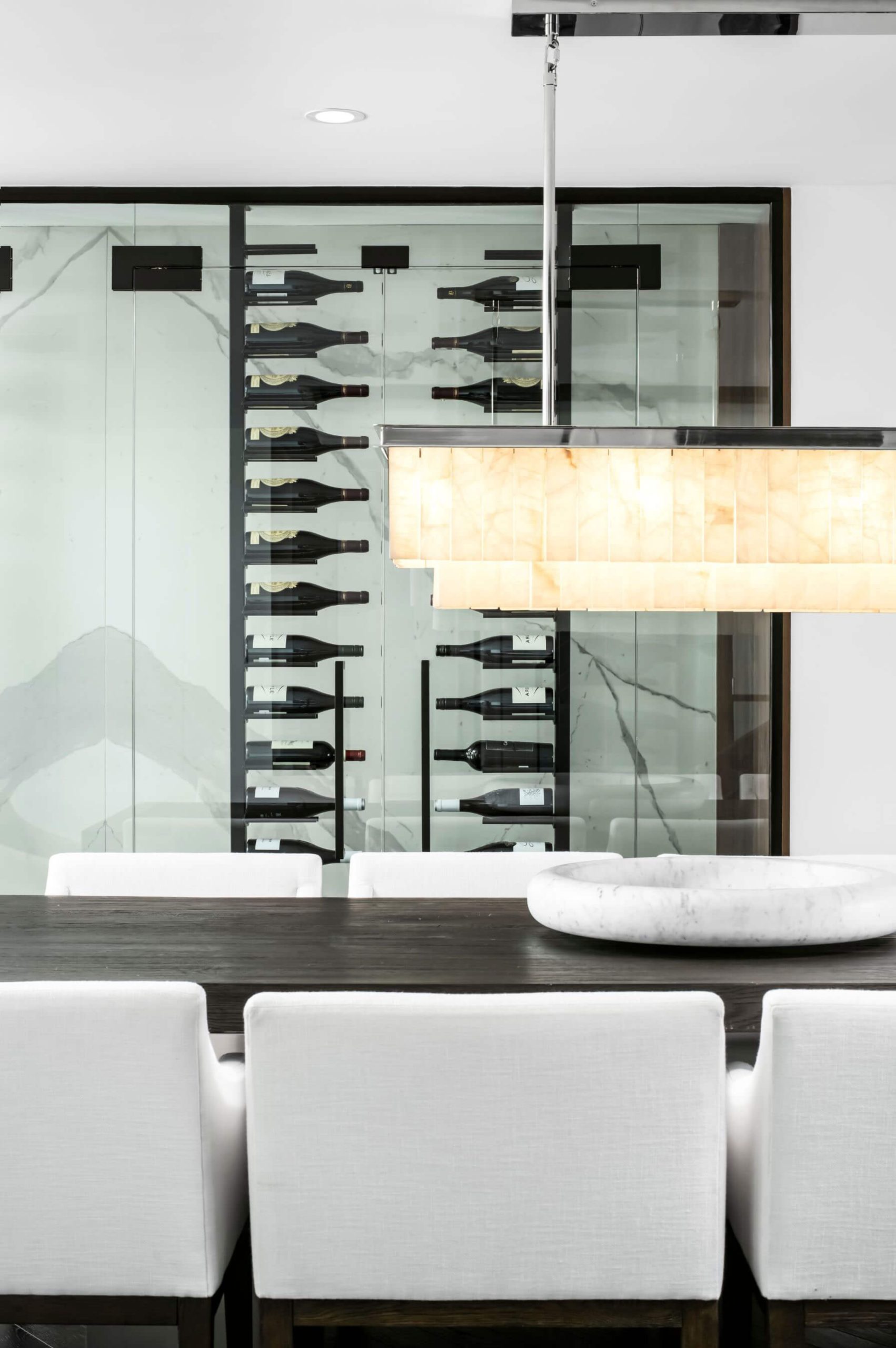 Dining chairs and glass wine storage beneath pendant lighting