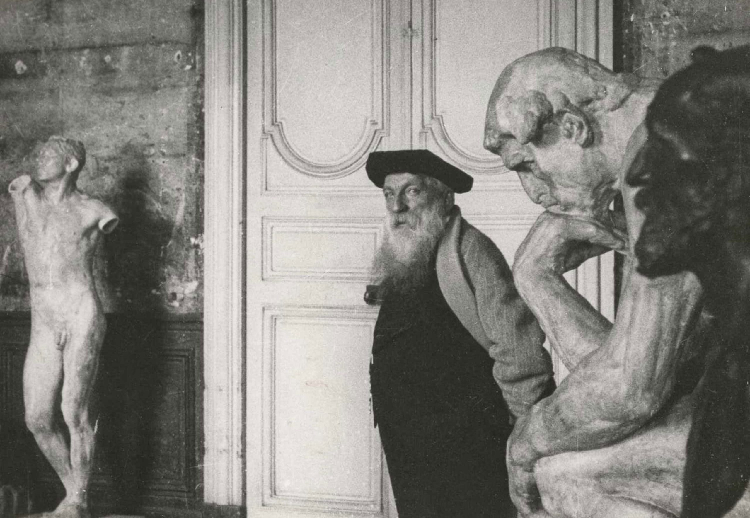 Auguste Rodin standing among sculptures in his studio