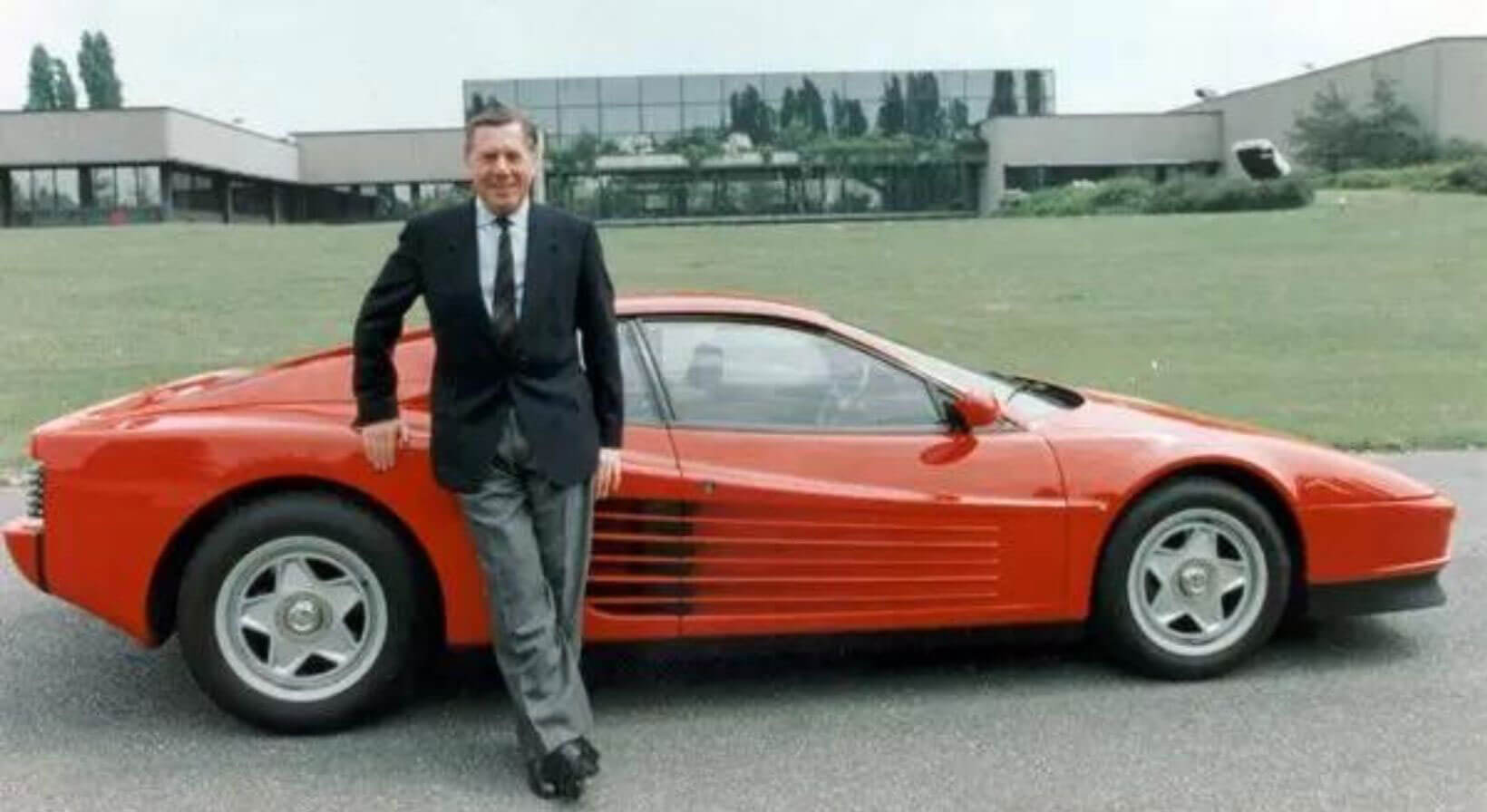 Man standing beside a red sports car