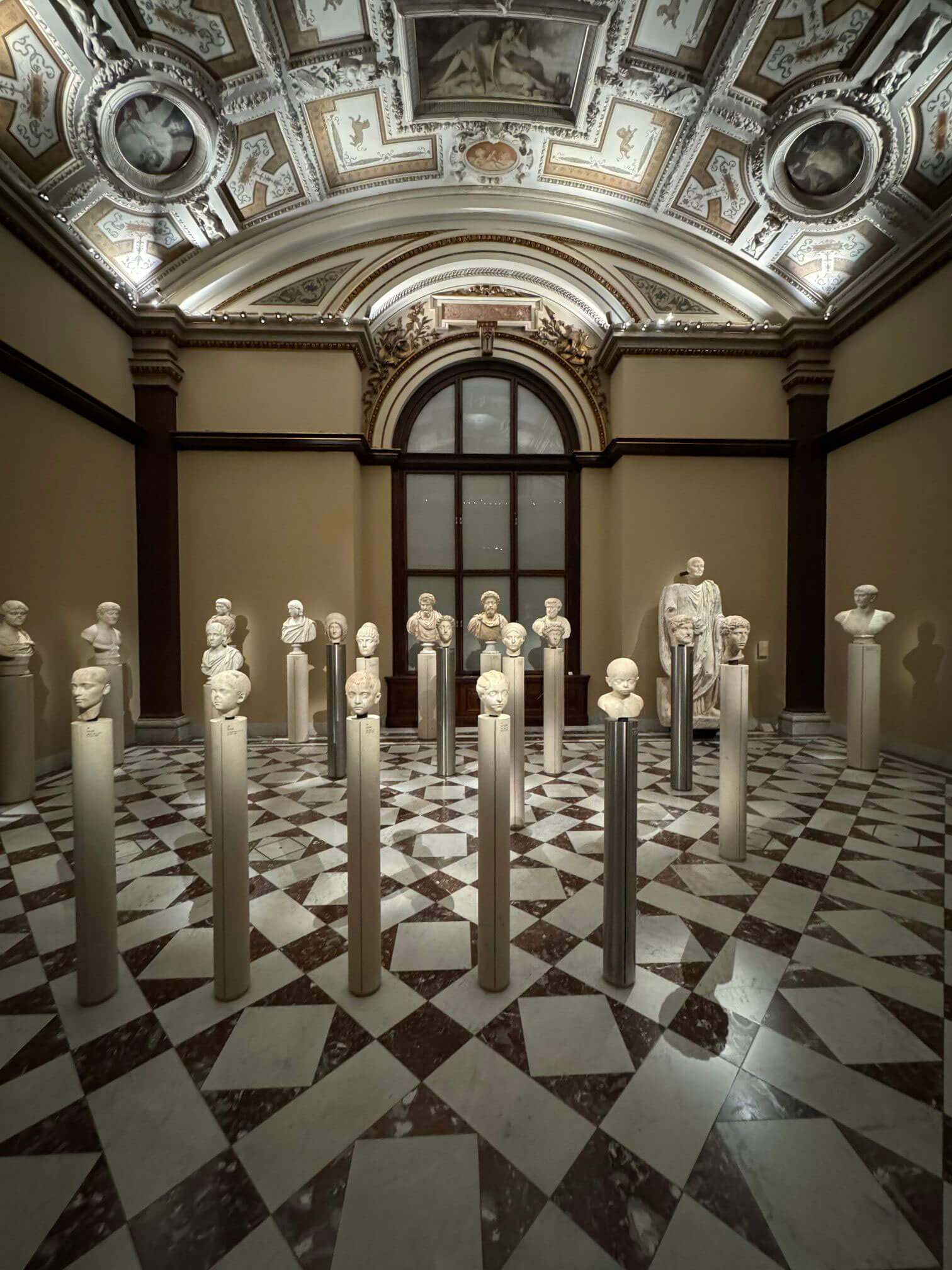 Classical sculpture gallery beneath an ornate vaulted ceiling