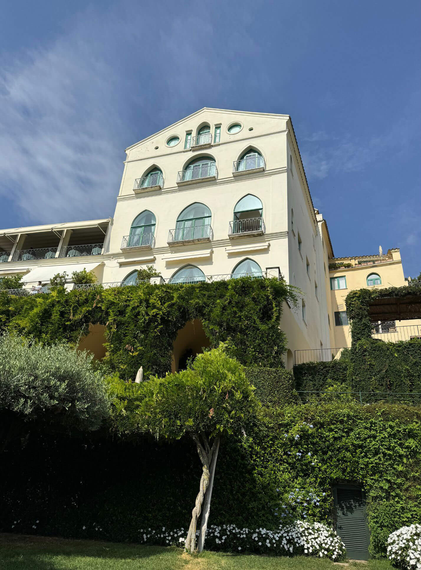 Pale hotel facade above terraced planting