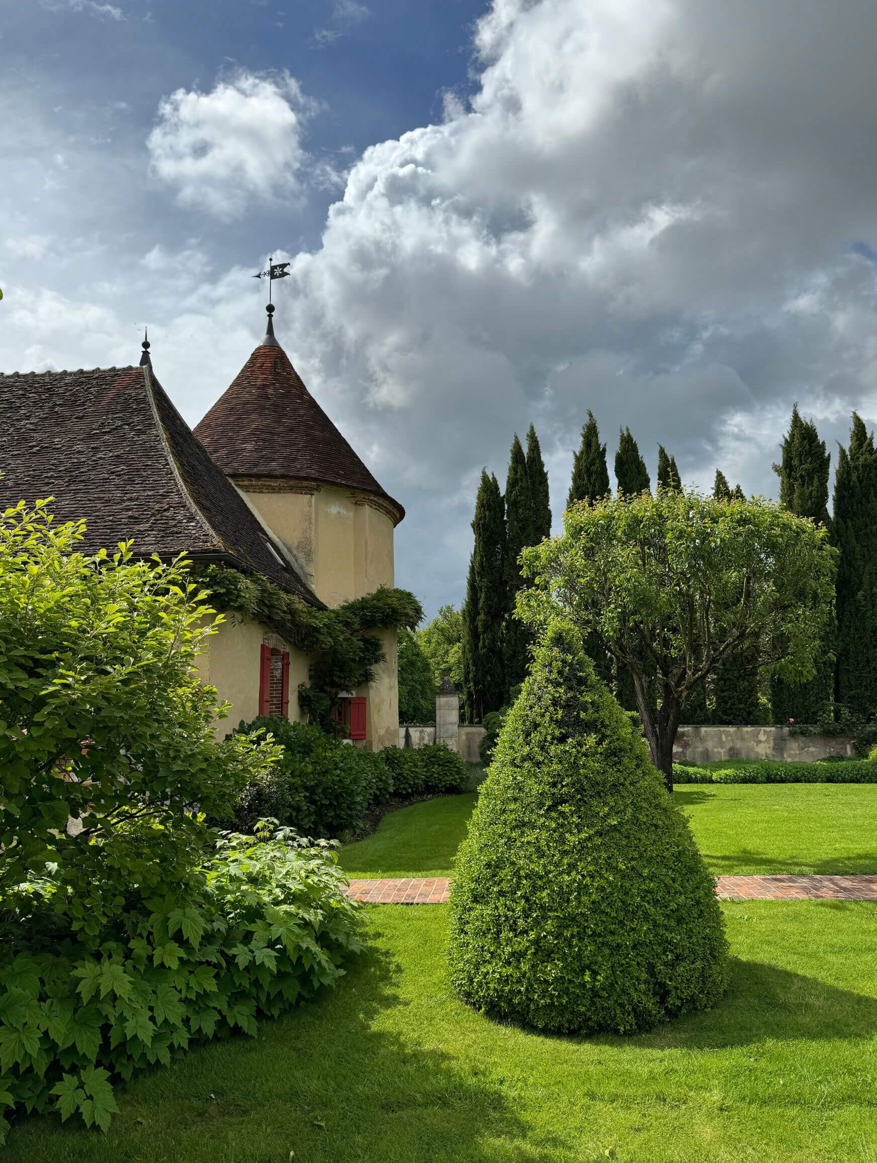 La Borde manor turret beyond clipped garden topiary