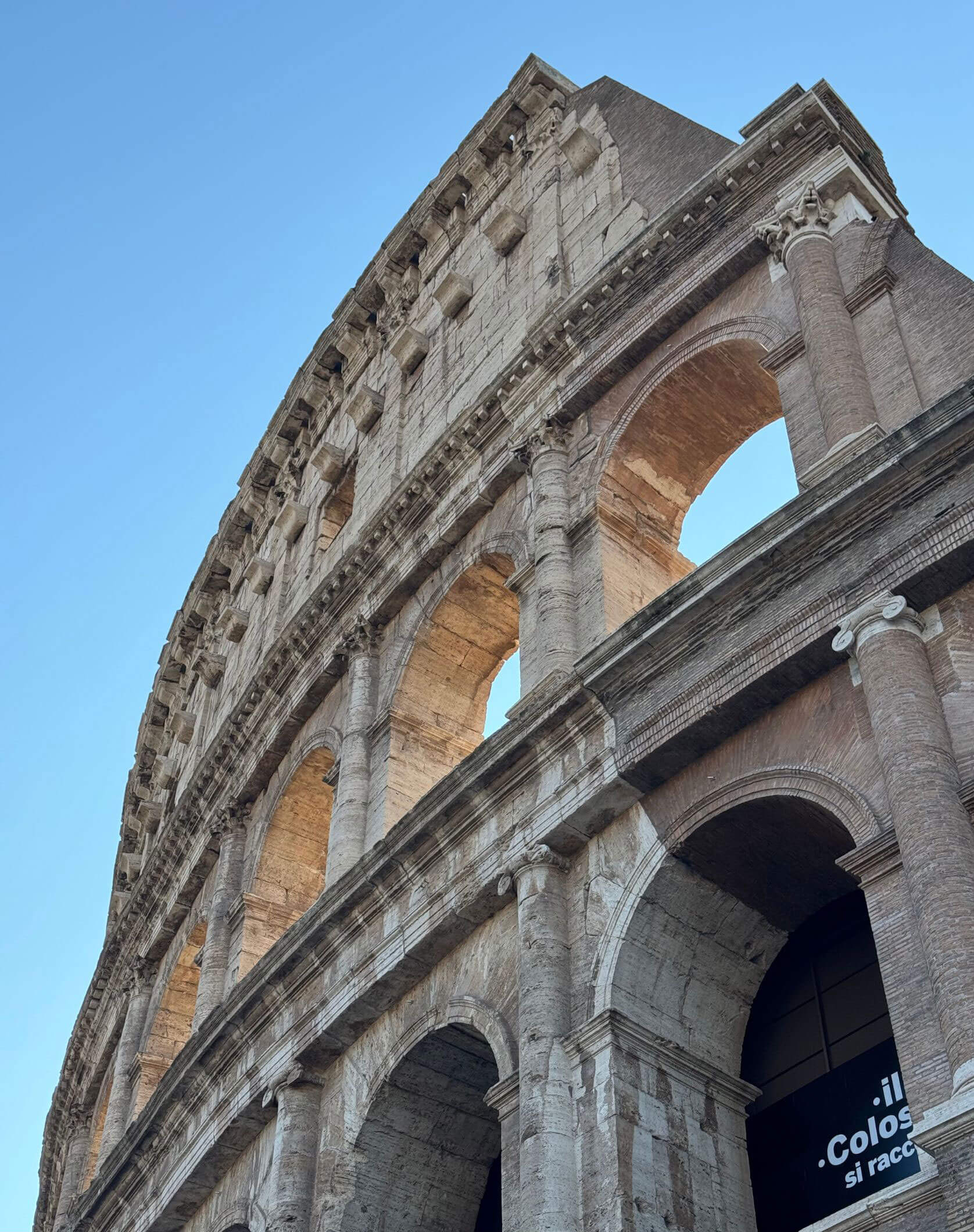 Outer stone arches of the Colosseum against blue sky