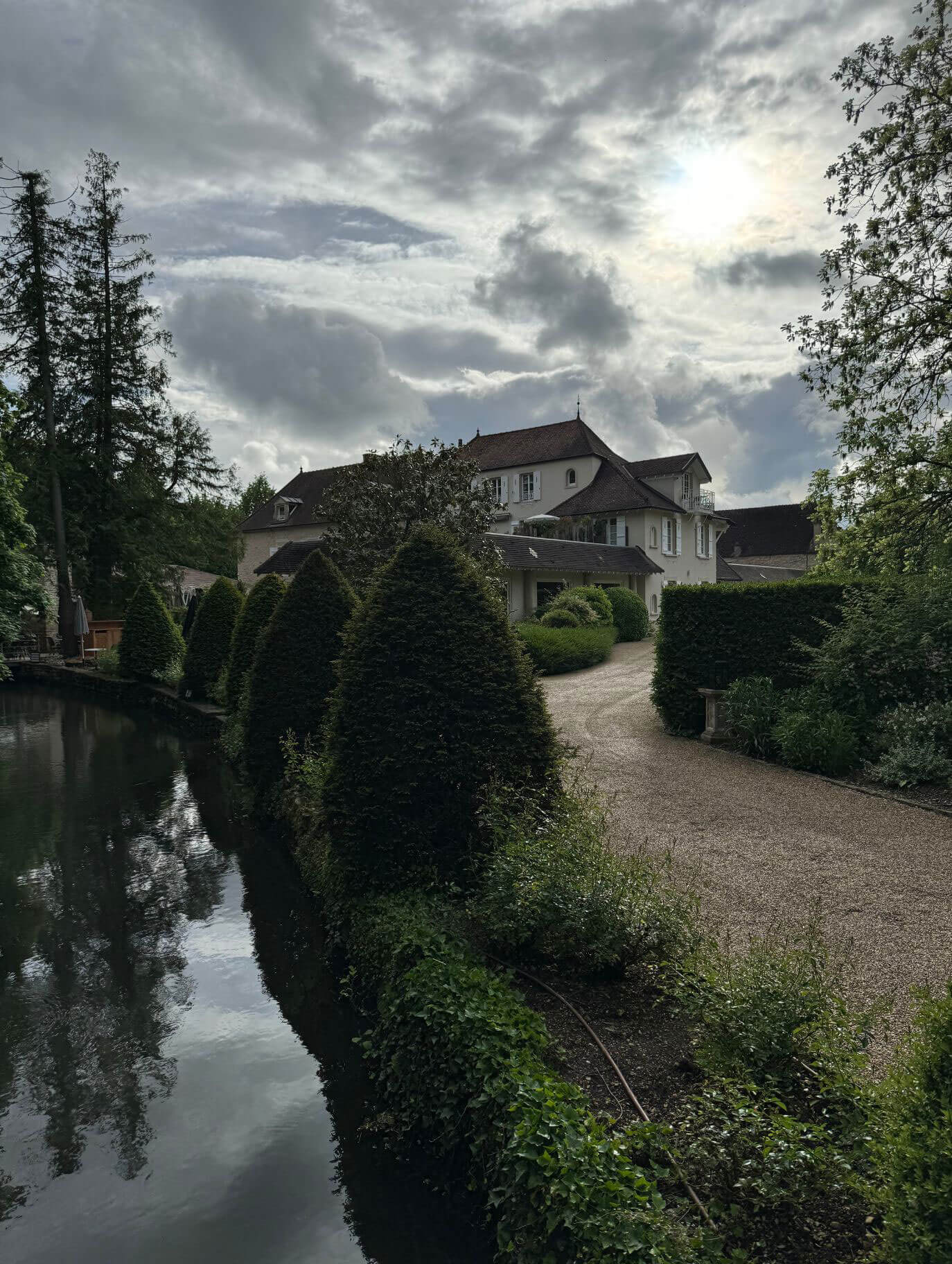 Garden path and topiary beside a shaded waterway