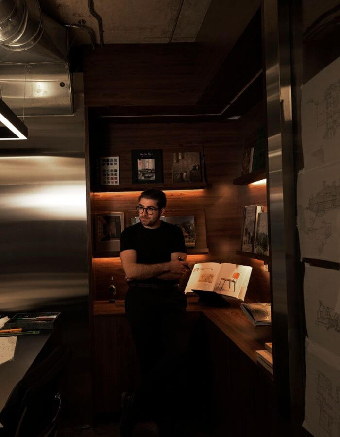 Jesse Sahlani standing beside an open sketchbook in a warmly lit studio