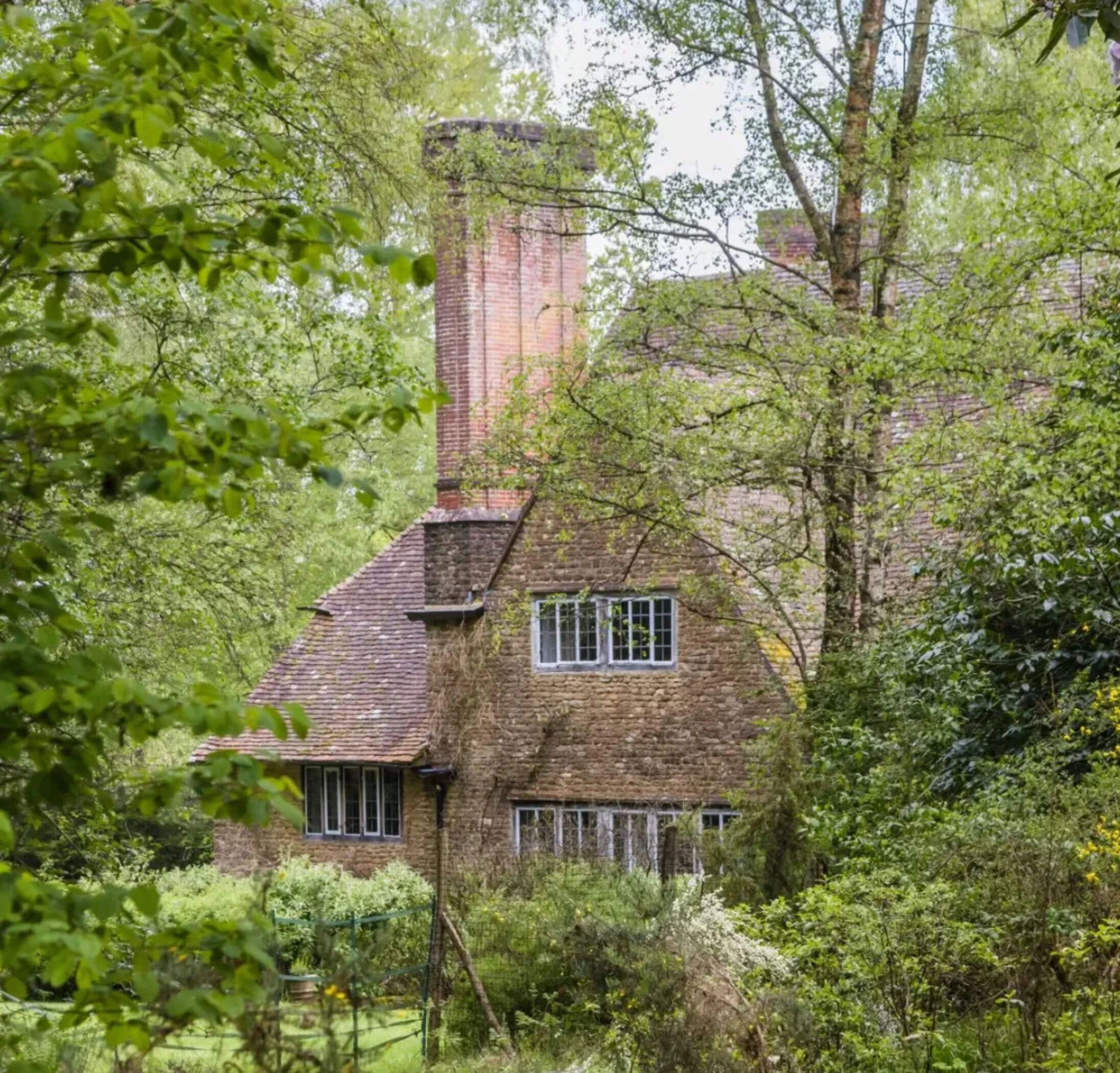Gabled brick house surrounded by trees and planting