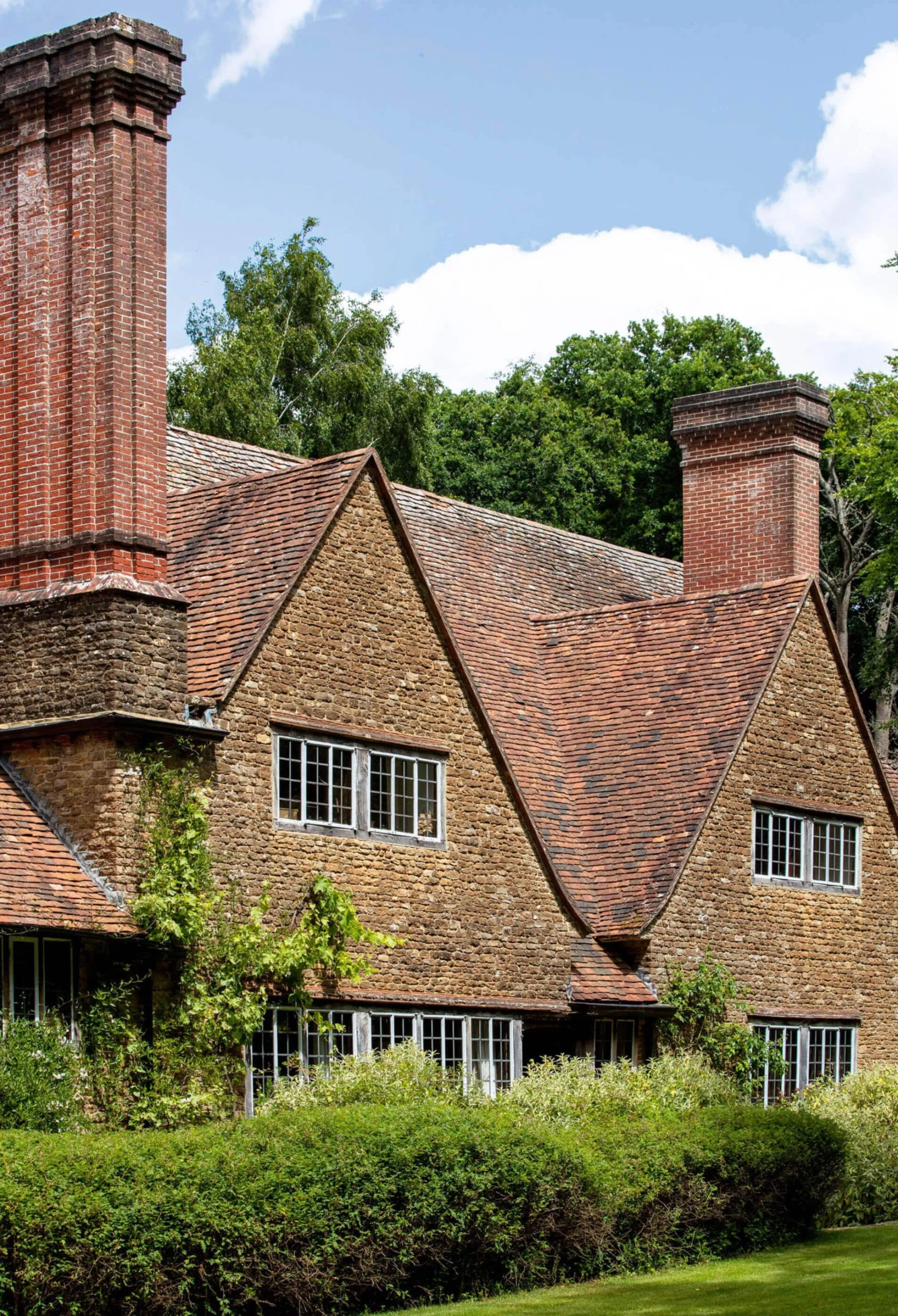 Steep tiled roofs and tall chimneys framed by greenery