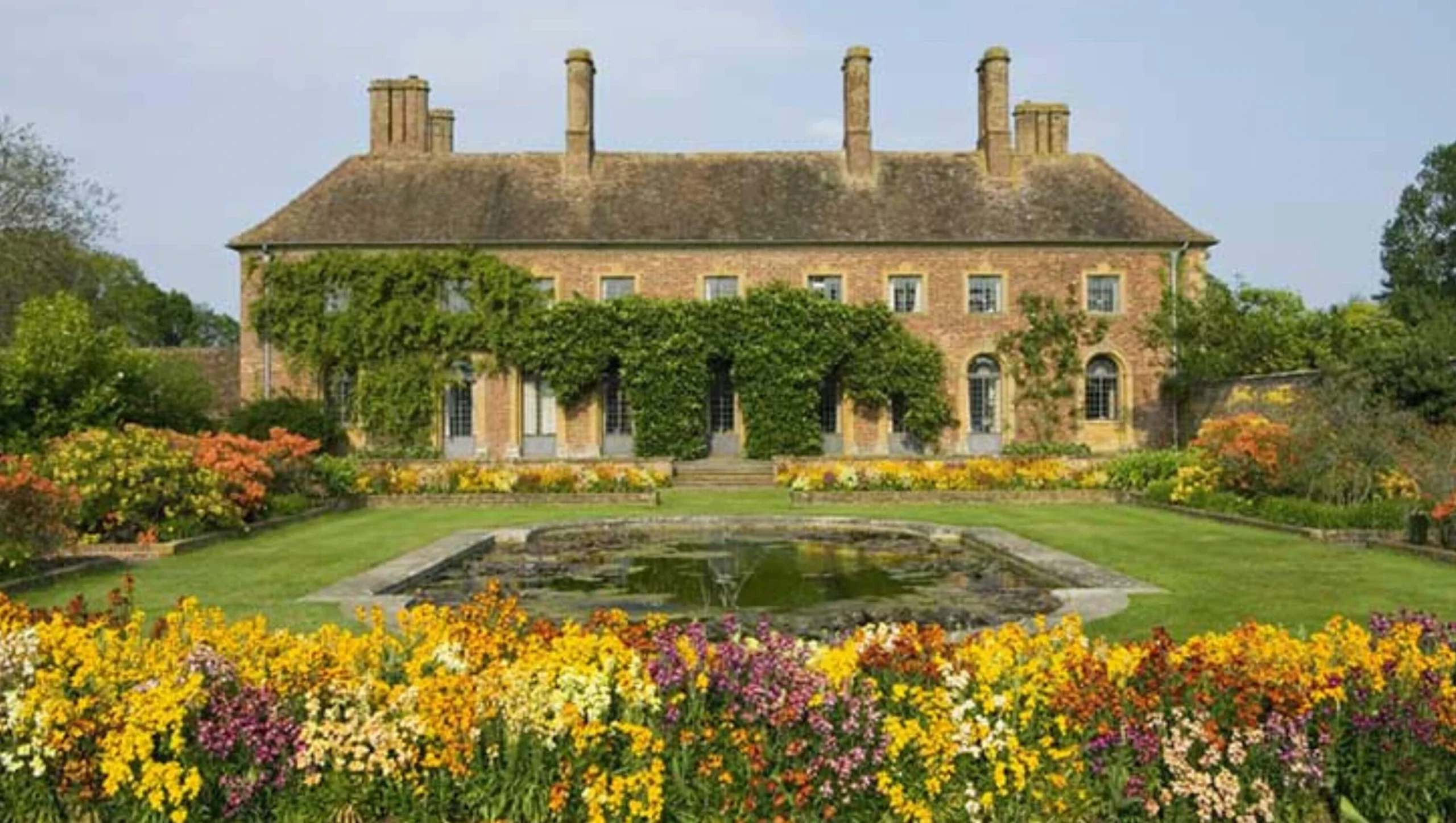 Stone manor overlooking a lawn and colorful flower garden