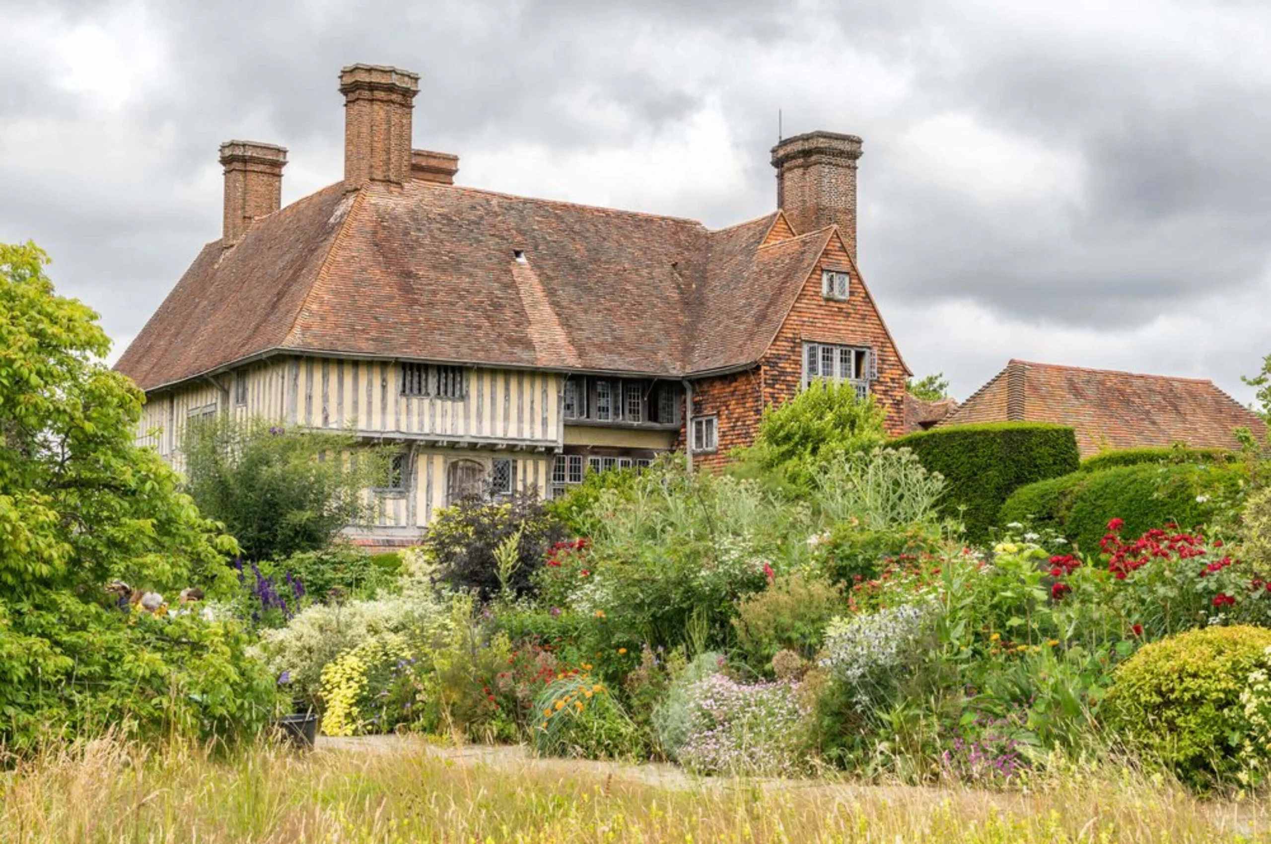 Country house with tall chimneys behind abundant planting
