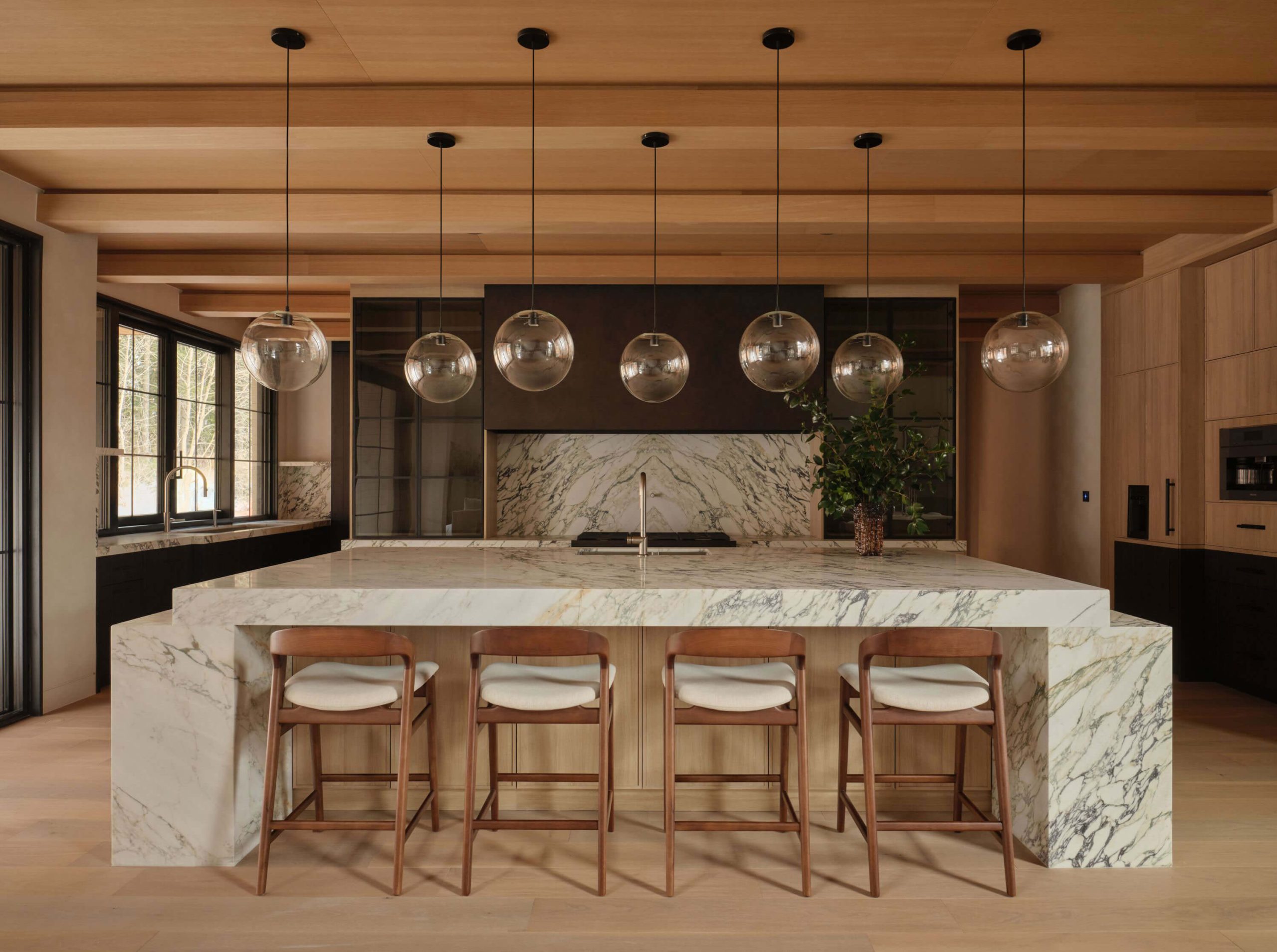 Warm timber kitchen with sculptural marble island and pendant lighting