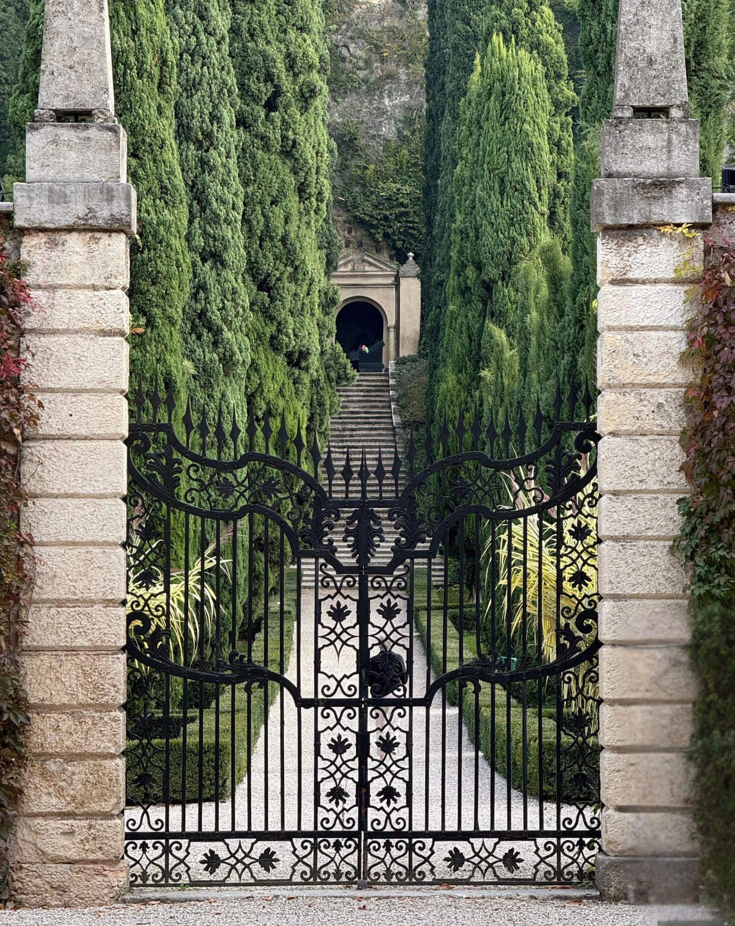 Iron gateway framing a cypress avenue and hillside steps