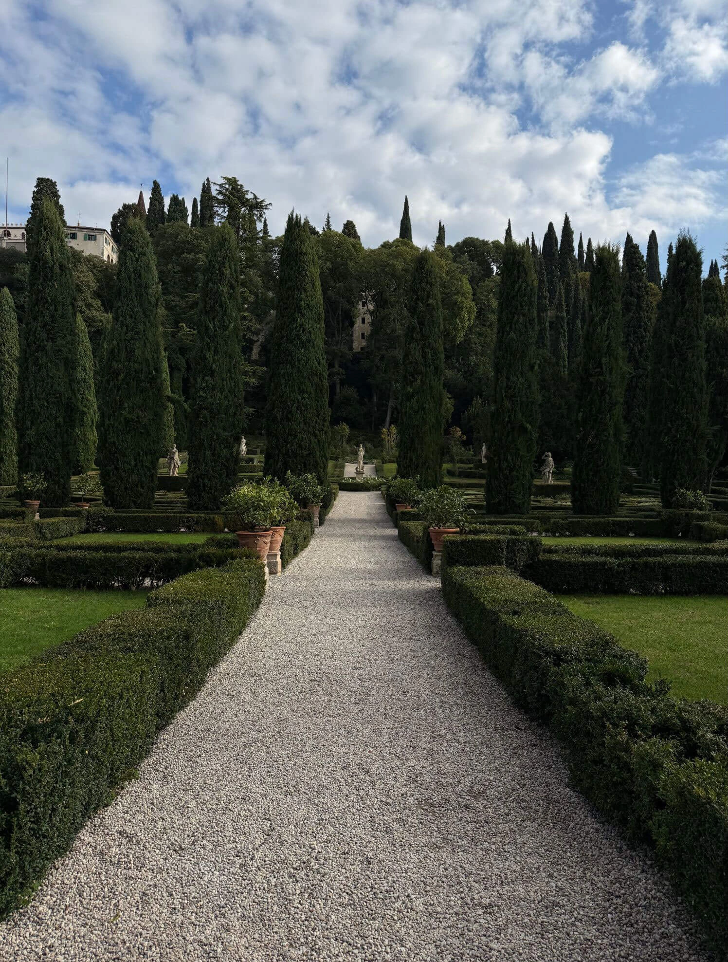Long gravel avenue through clipped hedges and cypresses