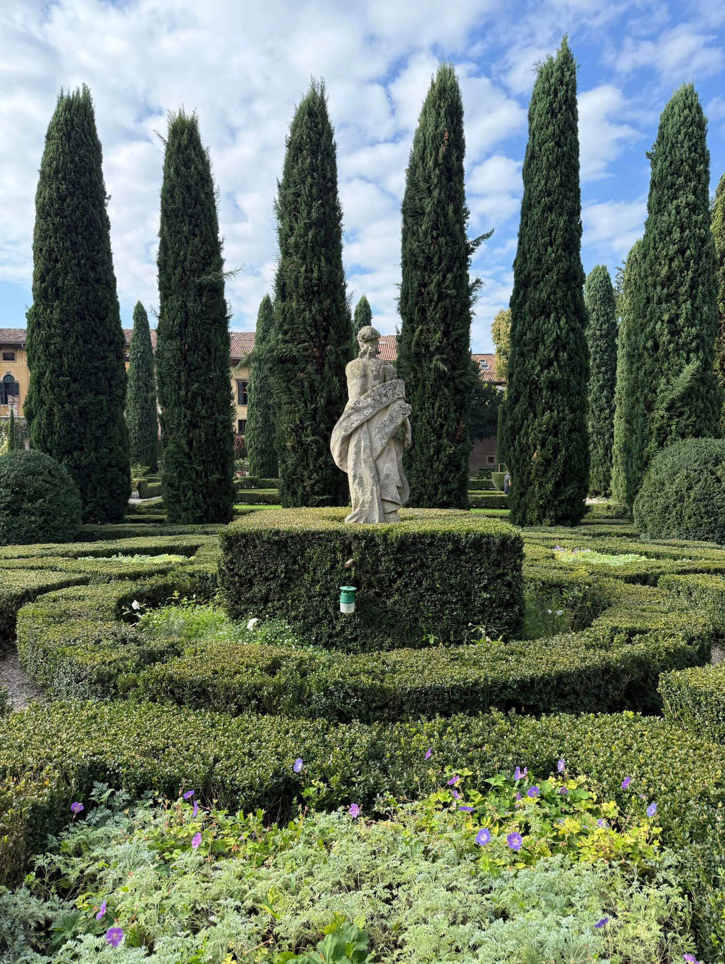 Classical statue among geometric hedges and tall cypresses