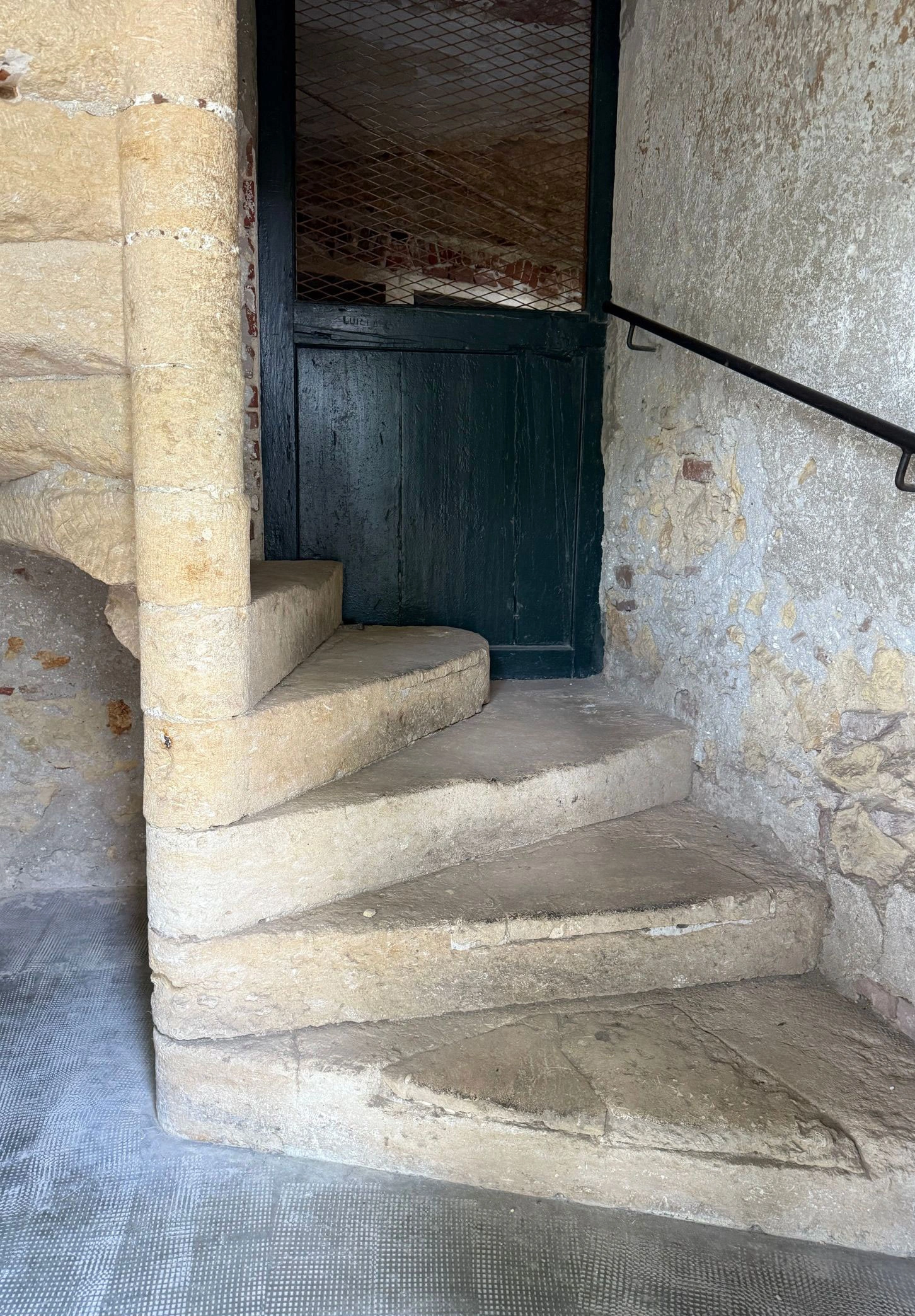 Curving stone staircase beside a dark painted doorway