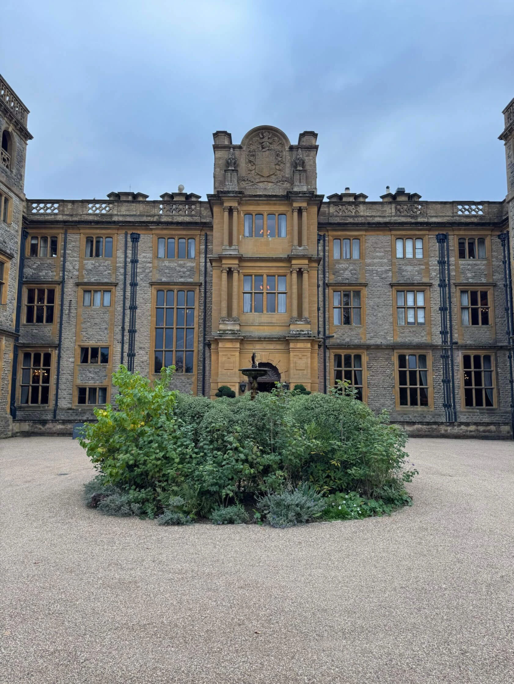 Stone manor entrance behind a planted circular bed