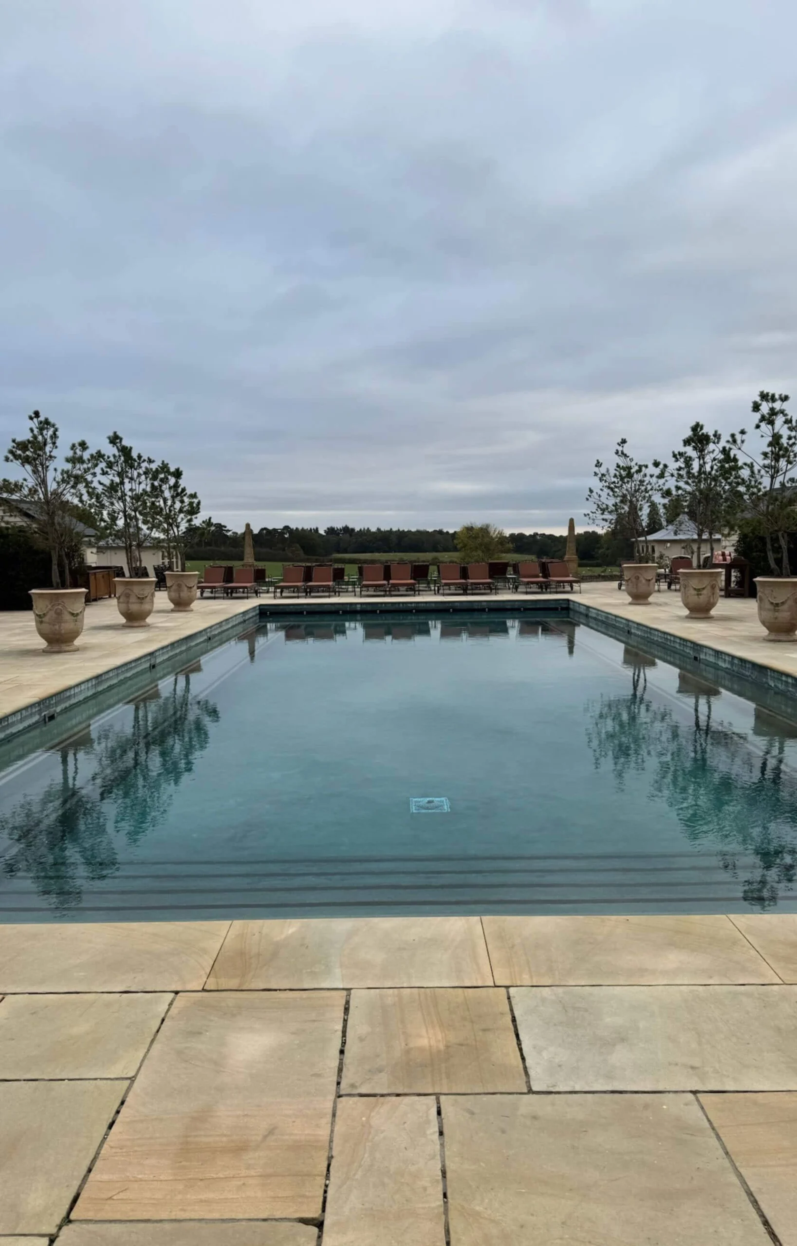 Long outdoor pool framed by pale stone paving