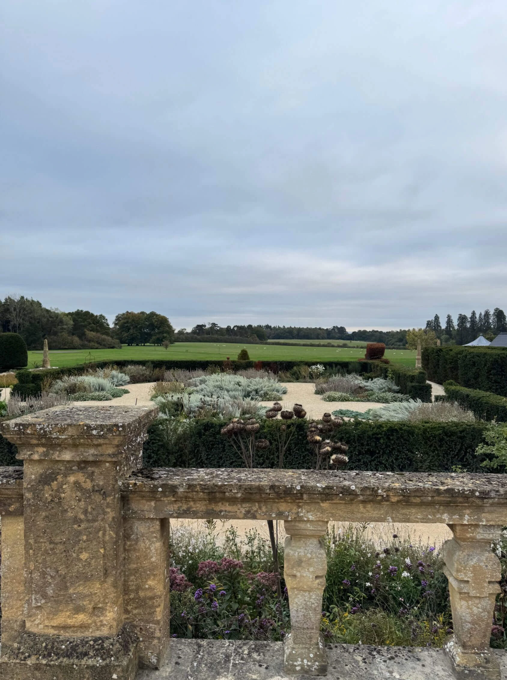Formal gardens beyond a weathered stone balustrade