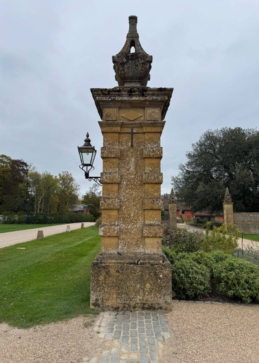 Tall carved stone gatepost beside a lawn