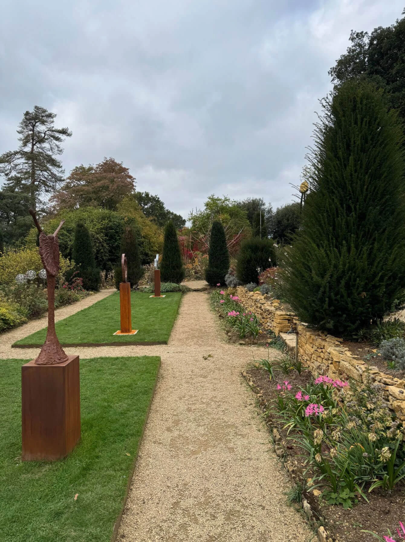 Sculptures on plinths alongside a gravel garden path