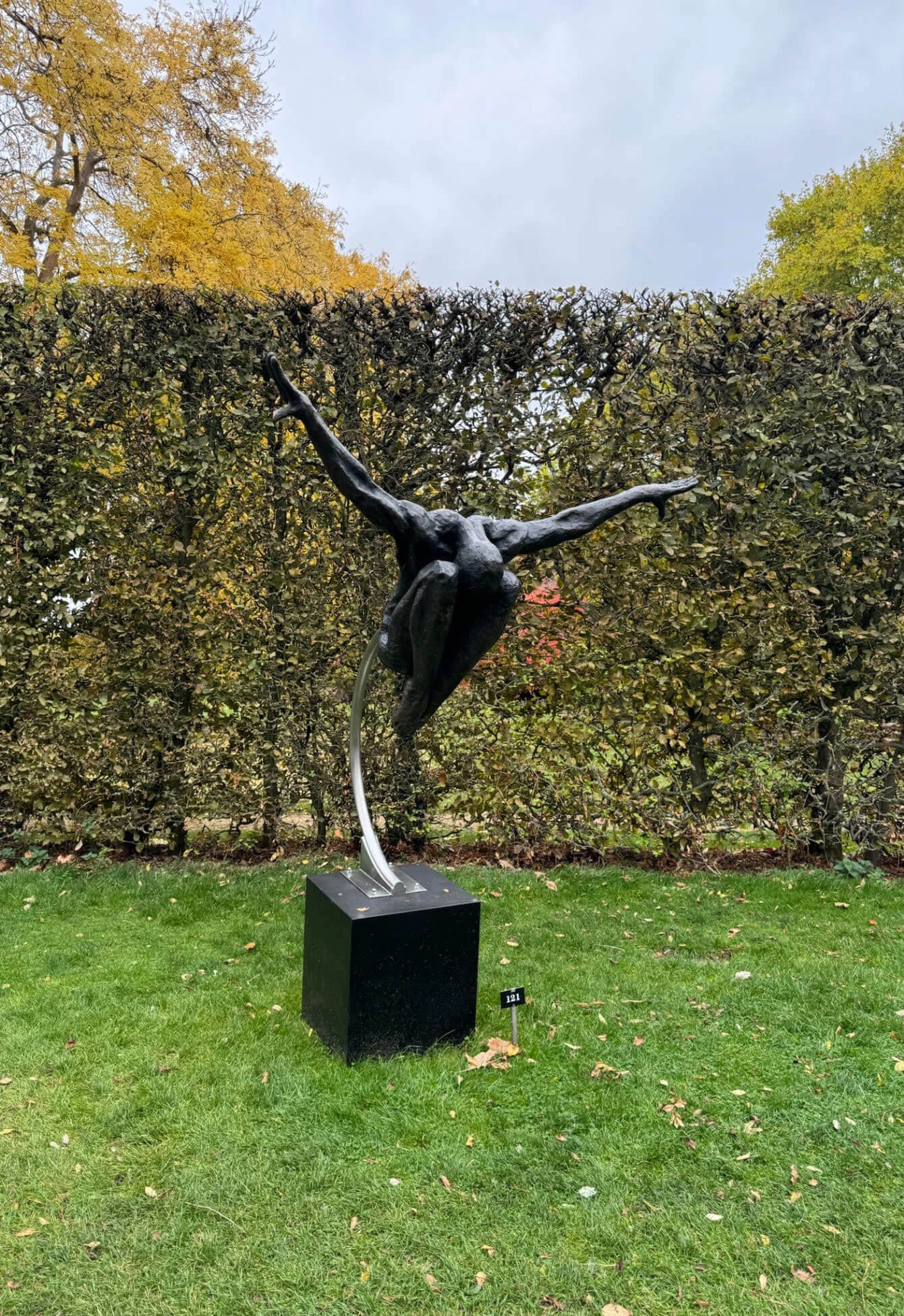 Bronze figure extending its arms on a garden plinth