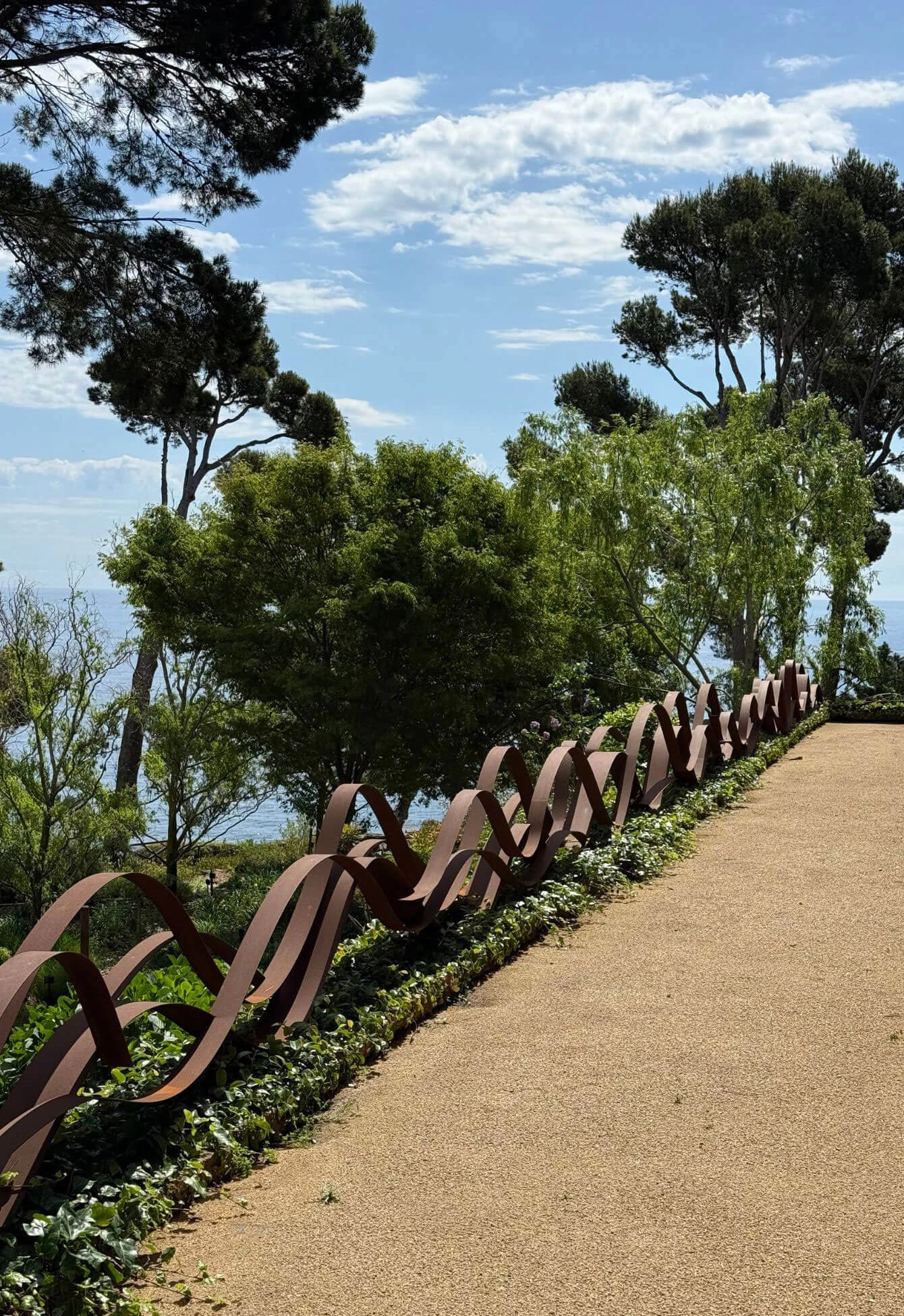 Repeating metal loops beside a planted garden walkway